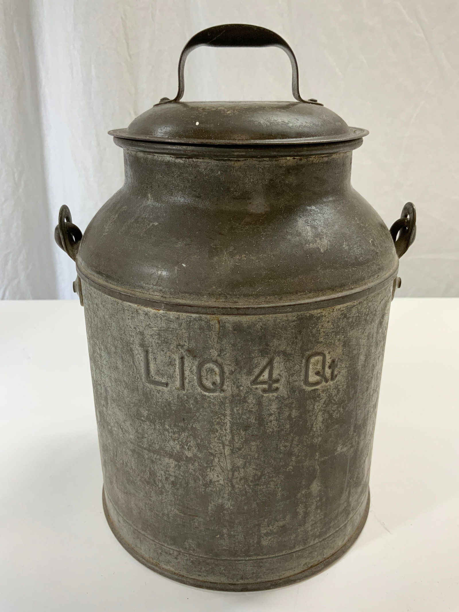 Vtg Four Quart Metal Milk Can W Handle 13in: Milk can is silver toned and metal. Piece is lidded and has arched handle. Front reads LIQ 4 QT. Piece is vintage possibly antique. With handle up measures approx 13 inches tall 8 inches wide. Milk ca