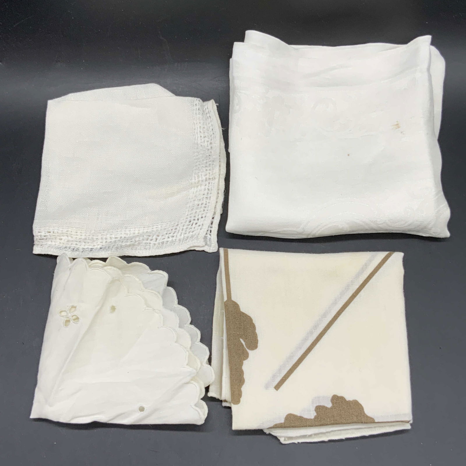 Lot 4 Vintage Table Linens, Fabric Napkins & More: Four vintage white hued table linens. Fabric napkins and fabric table accessories. Crafted from soft hand fabric. One napkin featuring foliage motif marked ALESSANDRO. Largest measures approx. 22L x 2