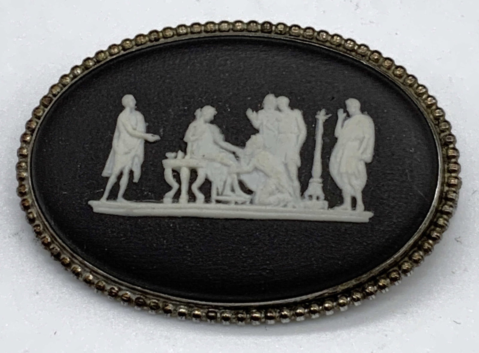 Vtg Wedgwood Black Basalt Grecian Brooch: Vintage Wedgwood black basalt brooch with white bas Relief Grecian figural motif. Setting tests for sterling silver using PuriTEST kit. Trademarked to underside. Made in England. Measures approx. 1 5/