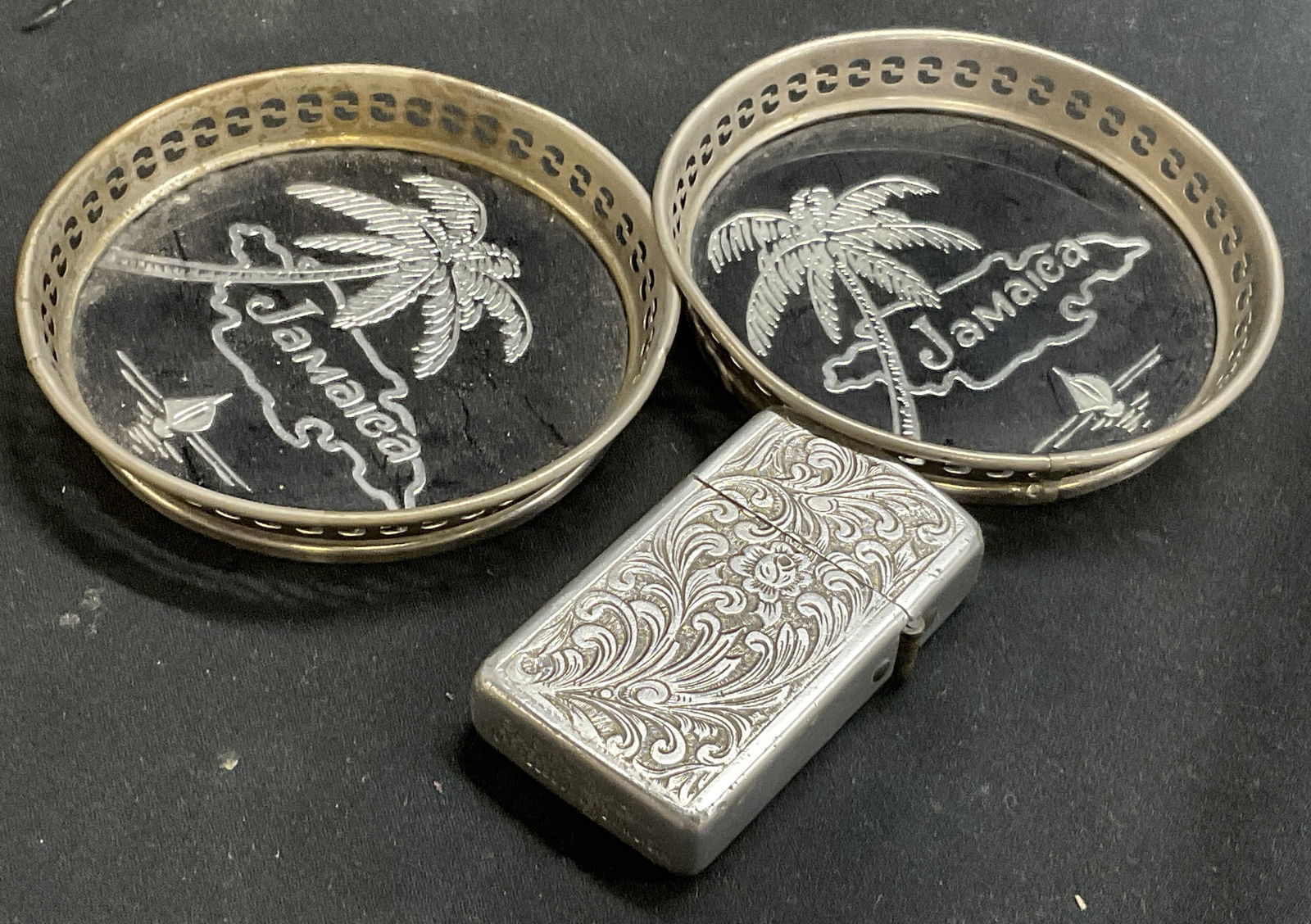 Lot3 Vintage Metal Accessories, Coasters & Lighter: 3 items crafted from silver tone metal. Two metal coasters with clear composite material covering the silver tone metal metal & black tropical design, palm tree, yacht and outline of Jamaica. Coasters