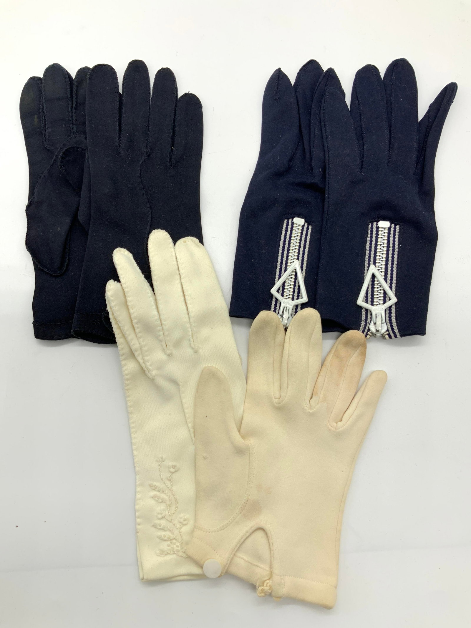 Lot 3 Pairs Vintage Cotton Gloves: Lot of 2 pairs of cotton gloves with 2 outliers. 1 pair of navy blue cotton gloves, approximately 8 inches long and 1 pair of Royal blue cotton gloves with white zippers on the backs. Approximately ap
