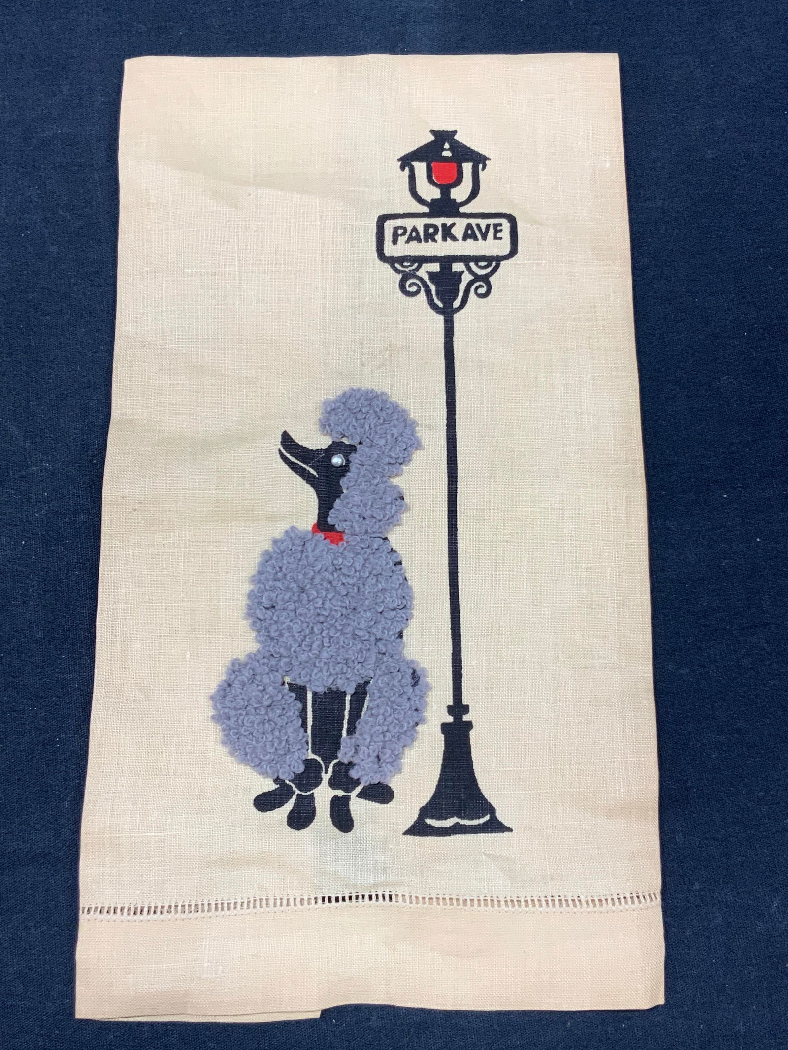 Vintage Poodle Embroidered Tea Towel: Vintage tea towel with an image of a grey fur poodle standing next to a street light that reads Park Ave. Poodles grey fur is embroidered within the linen. Approximately 20 x 10 inches Moderate blemis