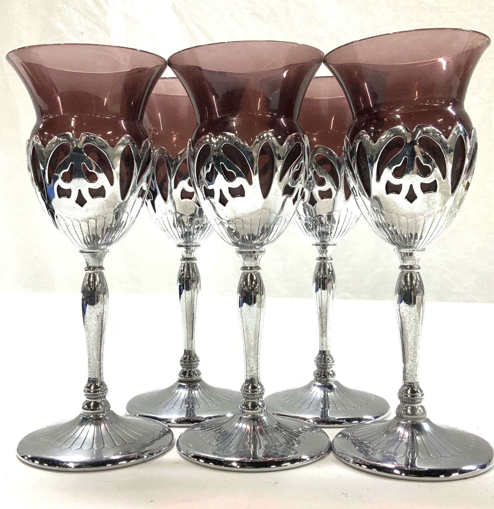 Set 5 Amethyst Glass Goblets in Silver Plate Stems: 6.5 in. Tall cocktail glasses/ wine glasses in amethyst colored glass goblets that are encased in silver plate stem and base . Glasses are flared at the edge, 2.5 in. Wide. and narrow to 2 in. W. Ligh