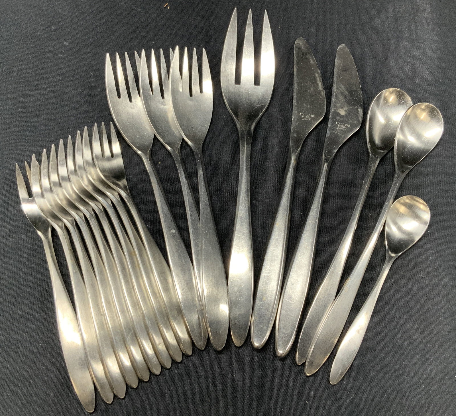 18 Stainless Steel Utensils, Japan: Lot of 18 Stainless Steel utensils. 9 Dessert forks, at 6 inches long, 3 dinner forks,7.5 inches long, 1 serving fork at 8,5 inches long, 2 knives, 2 stirring spoons, 8.5 inches long and 1 dessert spo