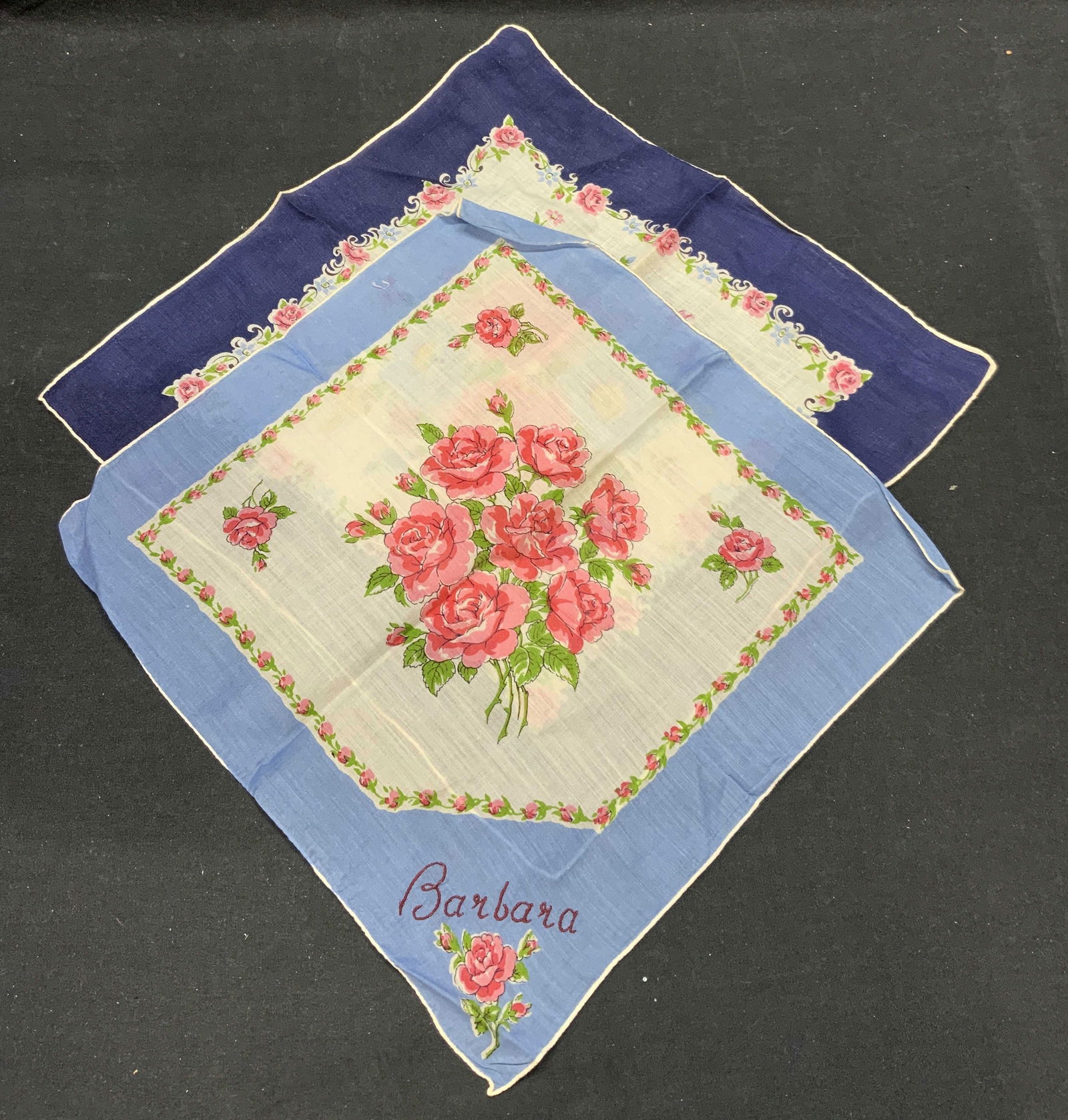 Lot 2 Vintage Blue Floral Handkerchiefs: Lot of 2 vintage handkerchief. Blue borders with floral motifs. Materials feel like cotton. One piece embroidered Barbara. Larger handkerchief measures approx. 13.75 x 13.5 inches. Some wear to materi
