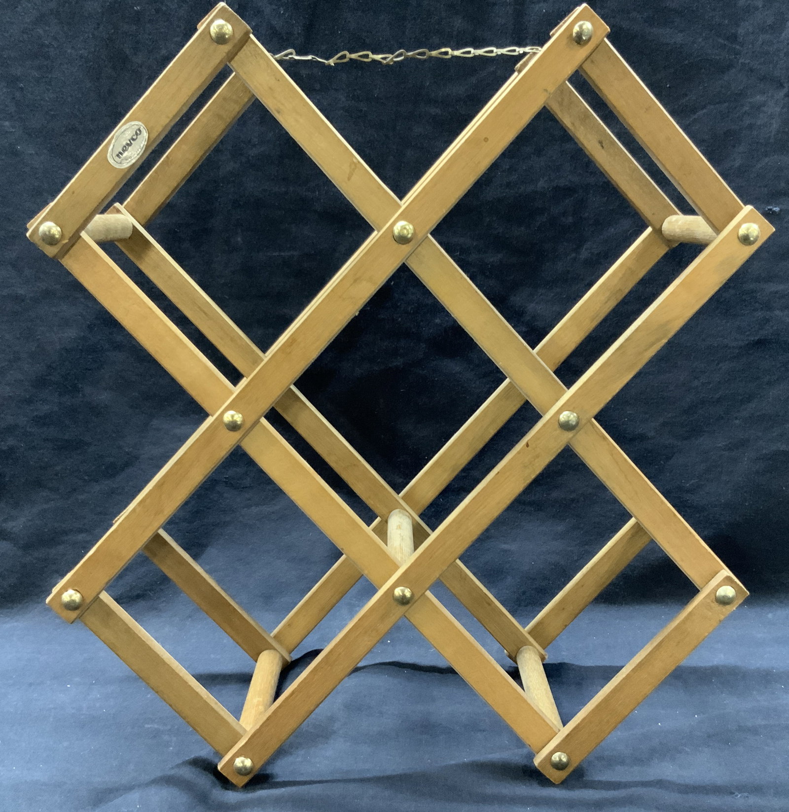 Nevco Wooden Fold Out Wine Bottle Rack: Marked on sticker Nevco. Wooden fold out bottle rack with chain to on top. Approximately 12 inches long and 5 inches wide released and 18 inches long when folded up. Moderate wearing due to previous u