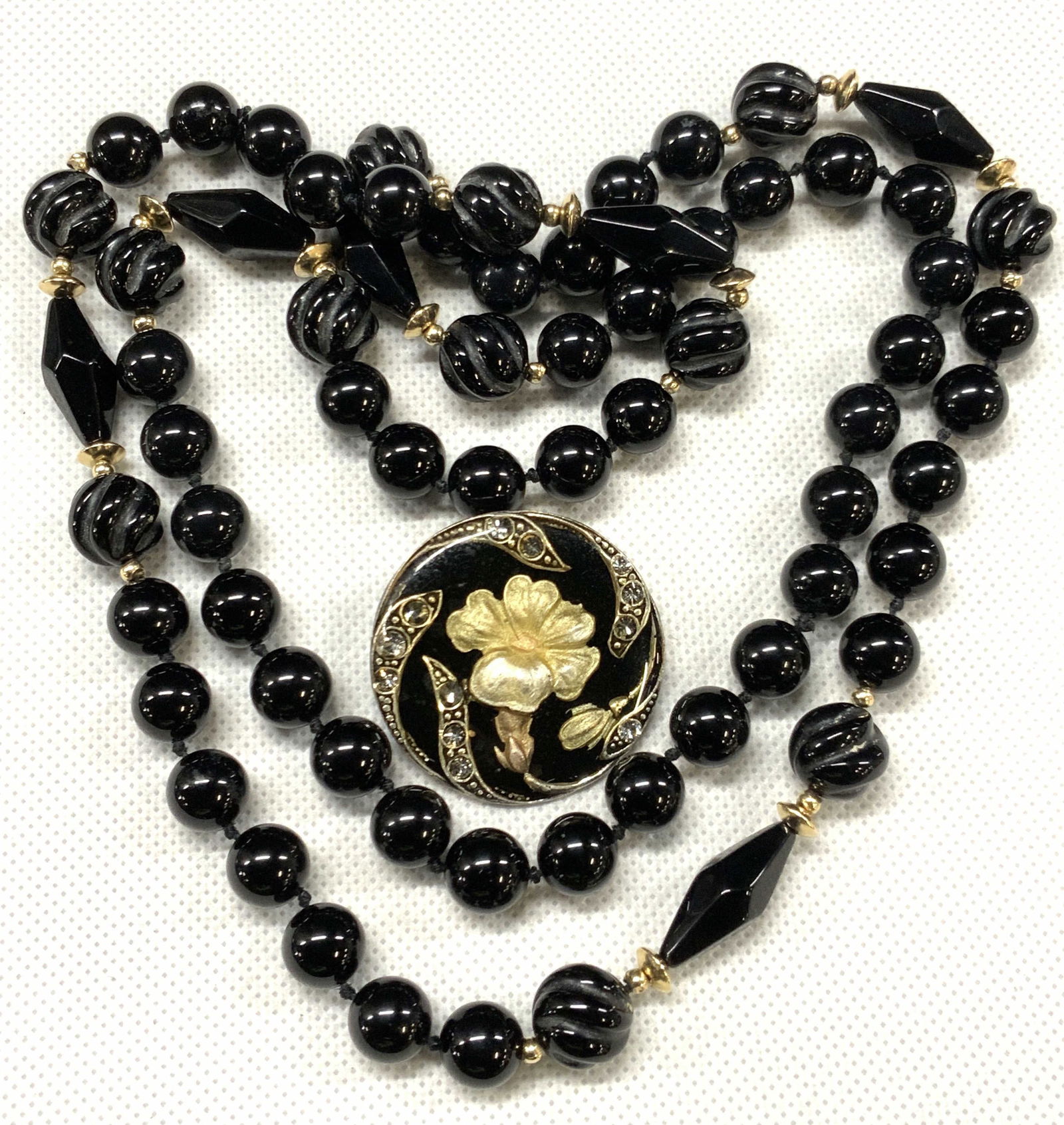 Black Stone Necklace & Sterling Enamel Brooch: Lot of 2 black toned jewelry. One sterling backed brooch with enamel and rhinestone obverse side. Backside Tests positive for sterling using Puritest metal tester and obverse side has white enamel flo