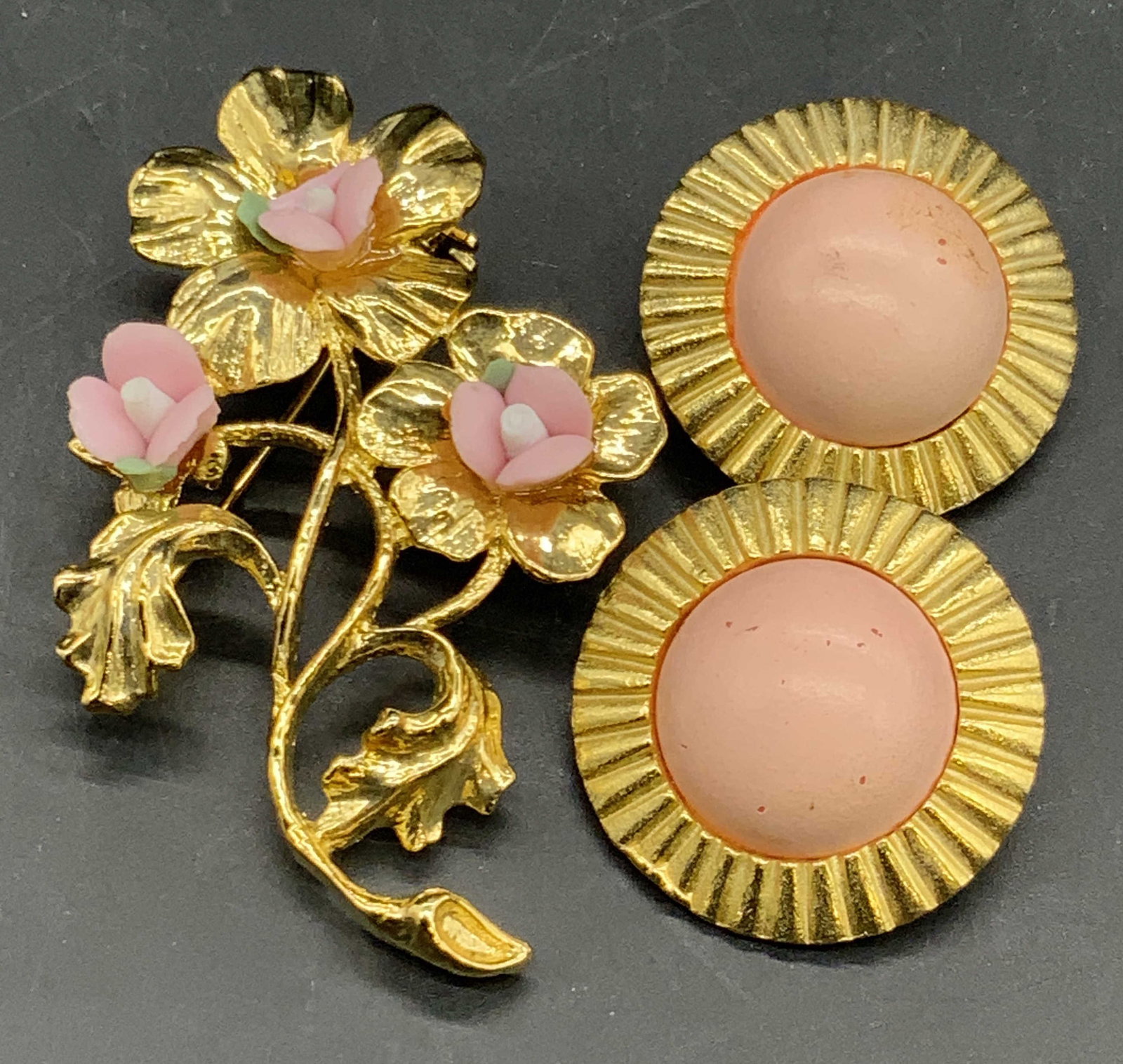 Lot 2 Vintage MONET Brooch & LANCER Pink Earrings: A vintage gold tone metal floral form brooch featuring raised composite pink and green florals, signed MONET on underside adjacent to metal pin closure. Measures approx. 2.25L x 1.5W in. Vintage circu