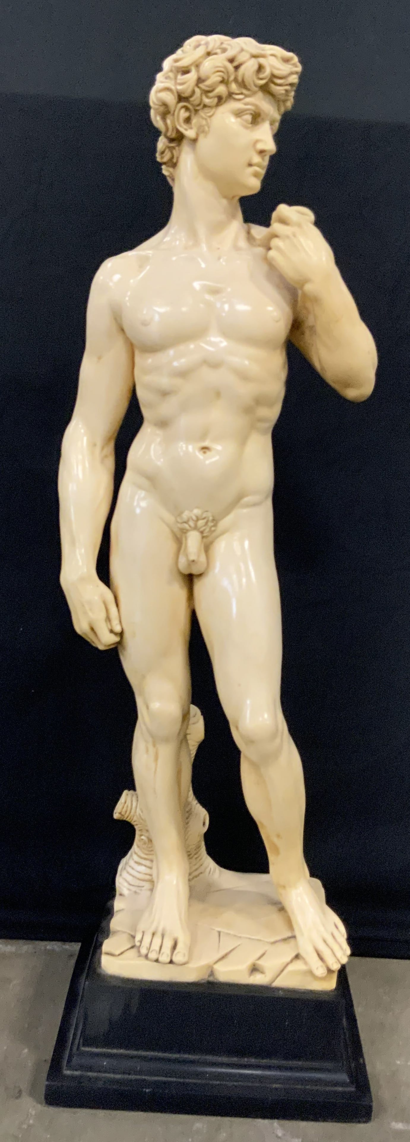 G. RUGGERI Statue Of David, 28 Inch Height: A resinous Statue Of David. David is a yellow-cream hue and stands atop a black base. Figure is depicted nude and holding a cloth over his shoulder. Reverse is signed G. RUGGERI. Measures approx. 28H 