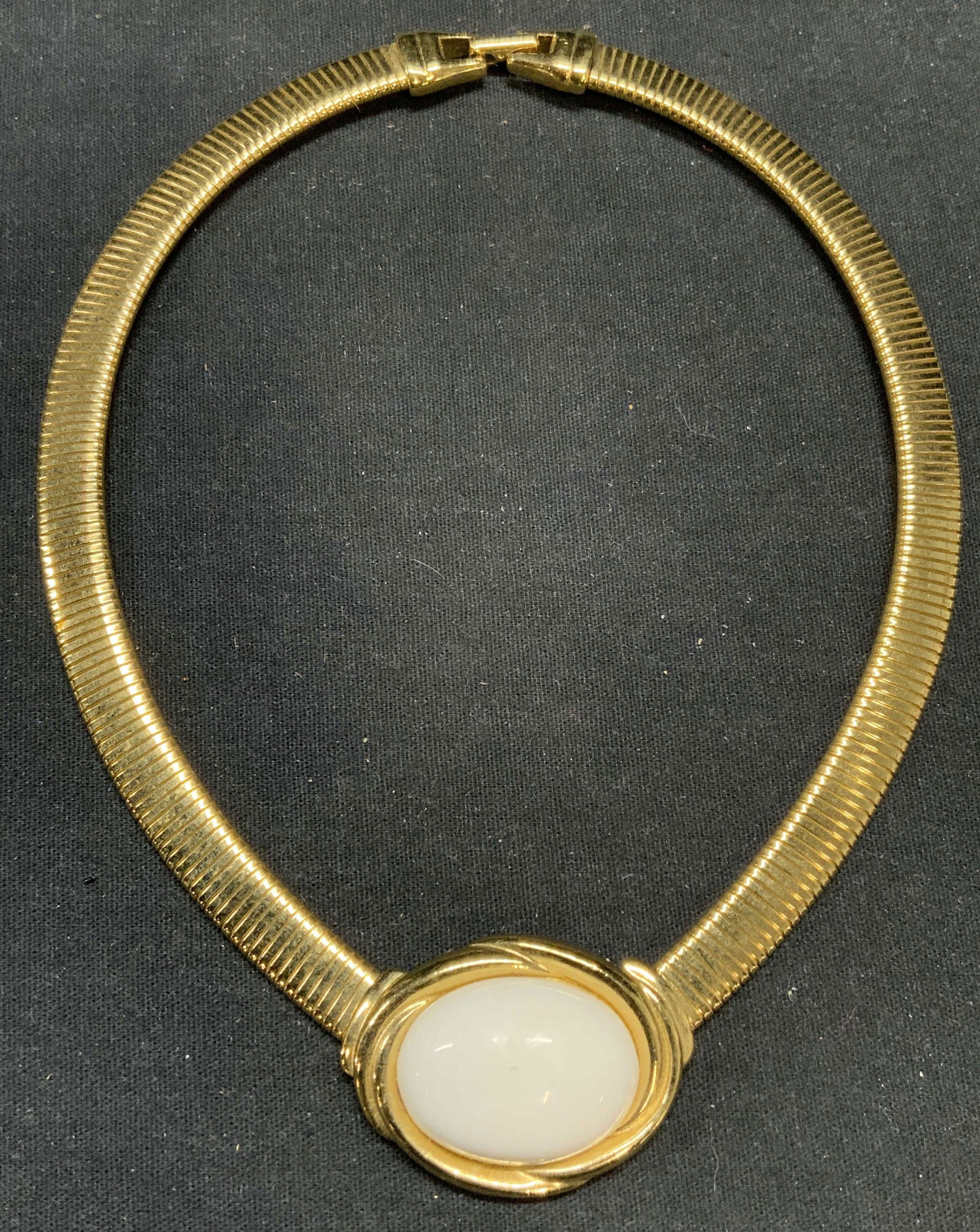 Trifari Gold Tone White Cabochon Choker Necklace: Vintage Trifari gold tone choker necklace with white Cabochon decoration. Drop length approx. 5 inches. Cabochon measures approx. 7/8 x 1 1/8 inches. Signed to underside of pendant and clasp. Some sur