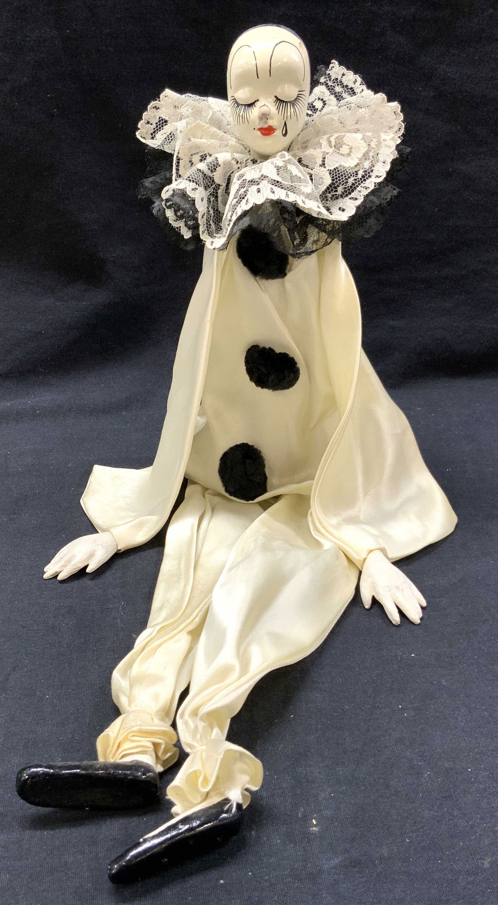 Art Deco Pierrot Clown Sitting Ceramic Doll: Vintage art deco Pierrot clown doll with formless arms and legs and solid center of the body that allows the doll to sit on a corner and dangle its legs. Porcelain made head with hand painted feathers