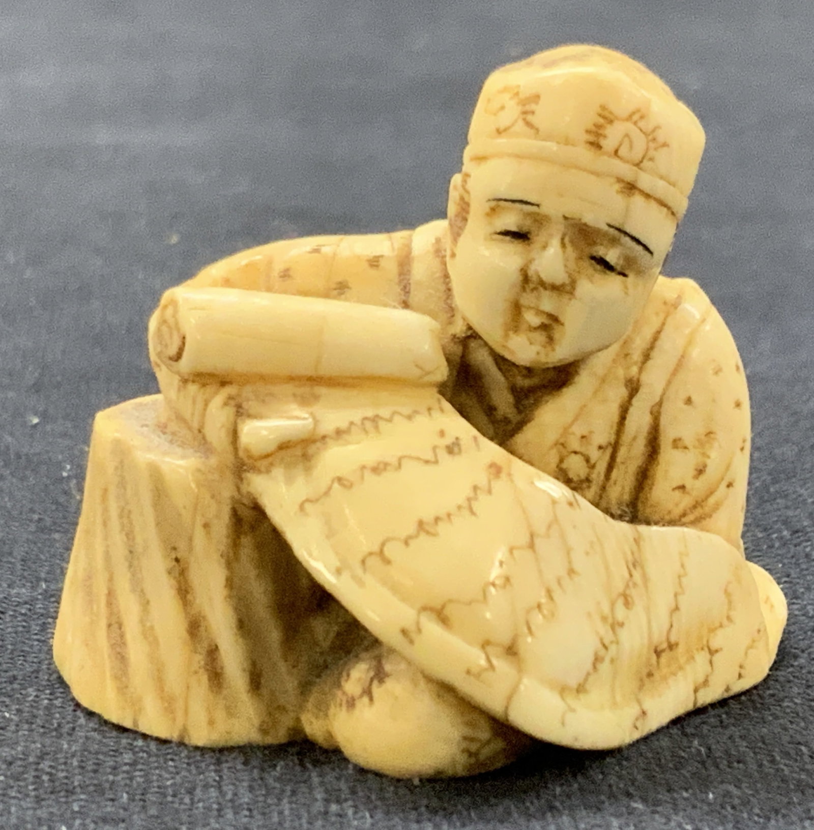 Signed Carved Bone Japanese Netsuke: Signed on underside with Japanese kanji. Netsuke depicts a man, possibly a scholar seated wearing a hat and high detailed robes holding a scroll in front of him. approximately 1 inch tall and 1.25 inc