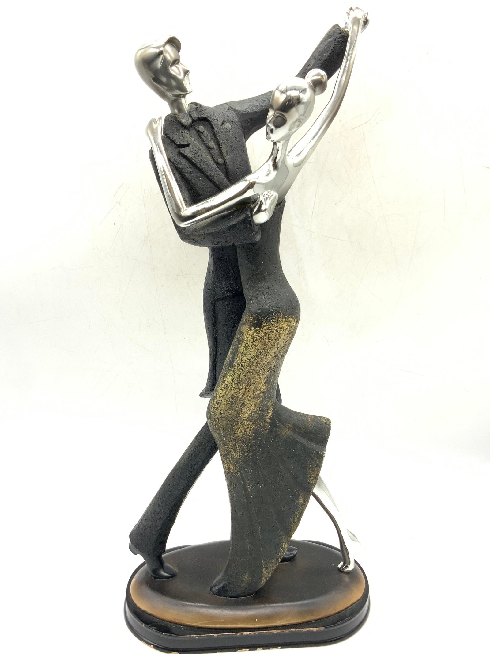 Art Deco Couple Dancing Sculpture: Art deco sculpture of a man and woman dancing, made of a resinous material with a metallic finish on the faces and skin of the figures with a wooden base. Approximately 16 inches tall and base at 8 x 