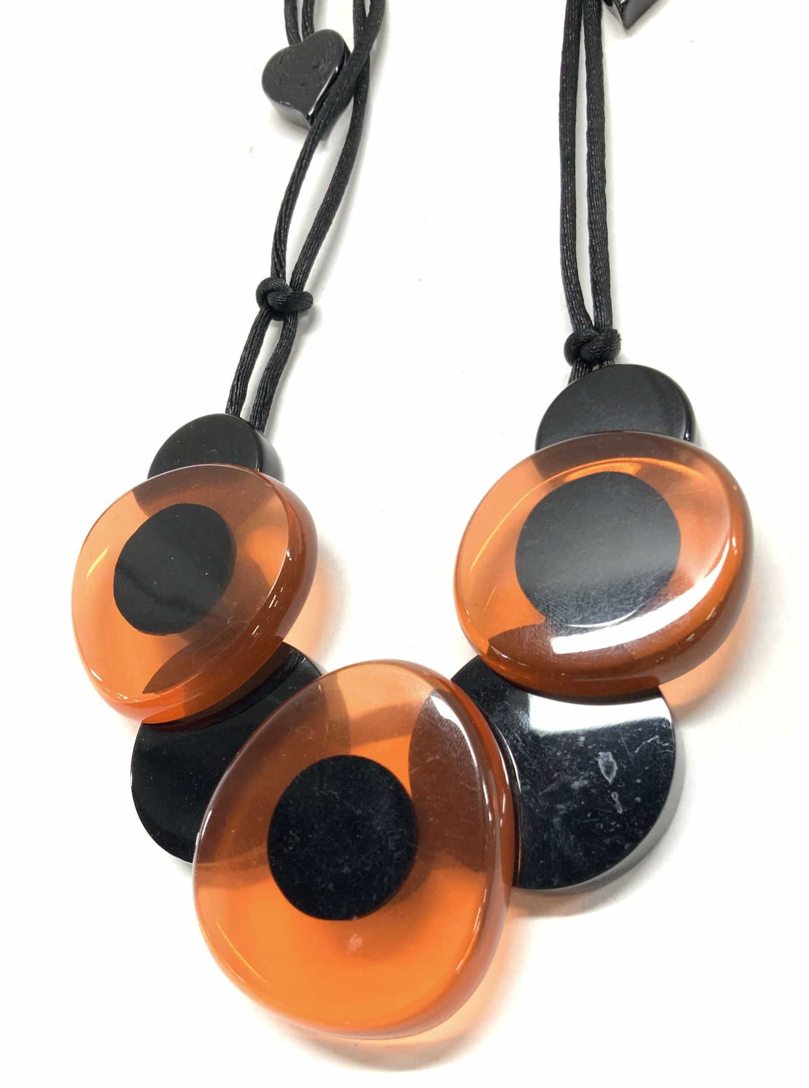 ZSISKA Orange & Black Lucite Necklace: Marked on end of cord, ZSISKA. Necklace has black ands orange toned Lucite pieces, affixed together with a black pull cord. Approximately 11 inches long, adjustable length. Moderate wearing and scratc