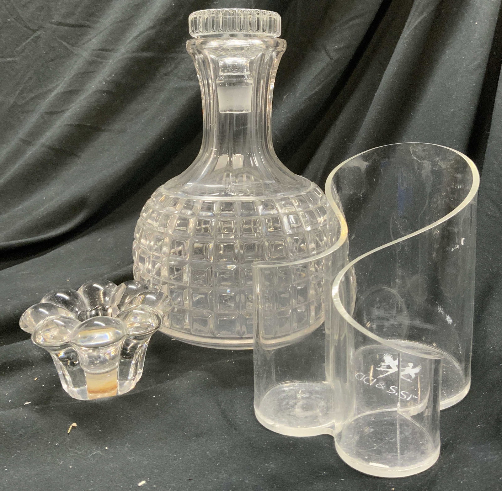 Lot 3 Decanter, Candlestick, & Pen Holder: Lot includes 1 Decanter, 1 pen holder, & 1 candlestick. Decanter is glass & has square pattern relief detail. Decanter includes stopper. Pen holder is trademarked CICI & SISI. Piece is plastic with cu