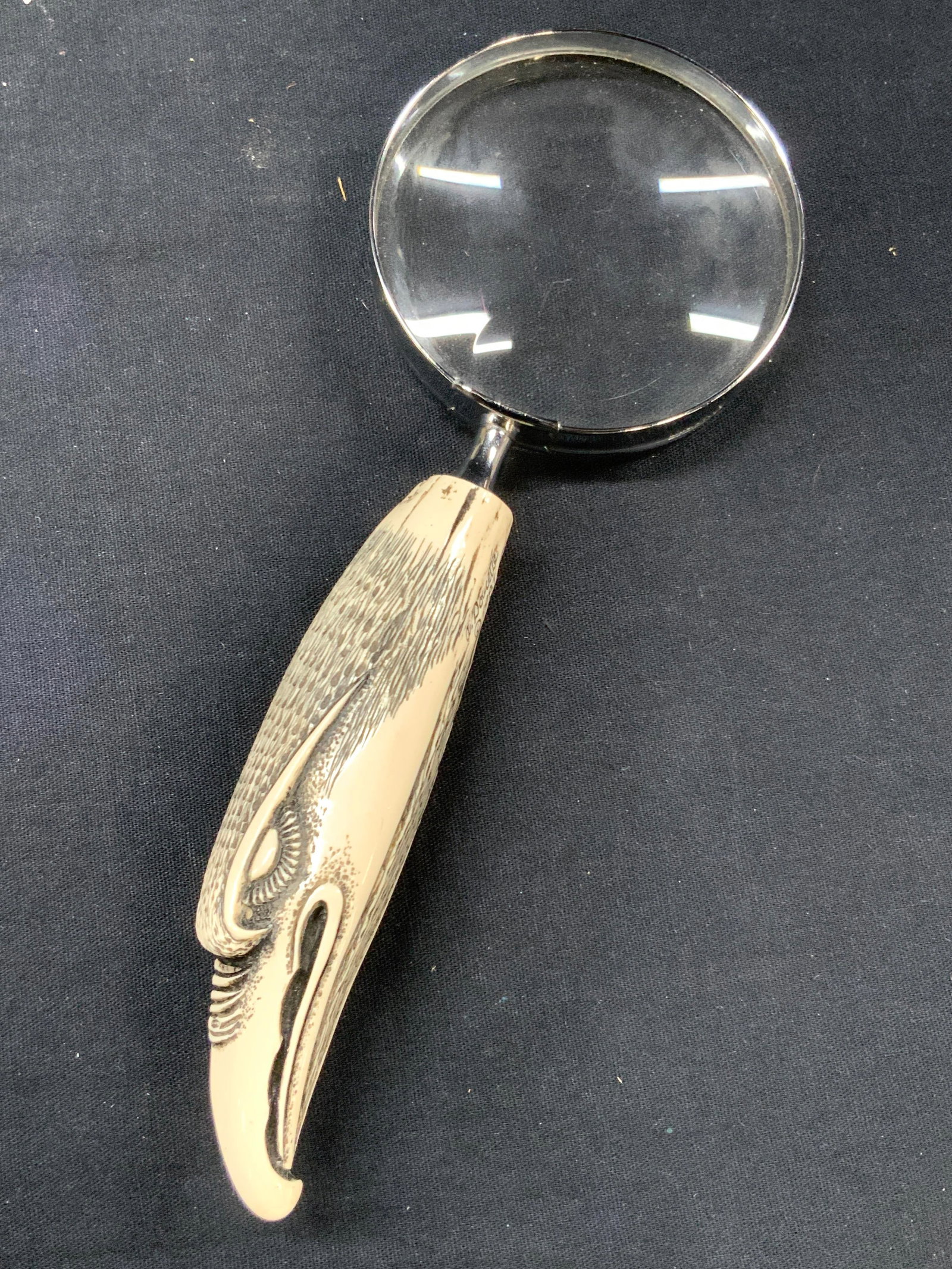 1987 Doucette Carved Eagle Handle Magnifying Glass: Carved handle magnifying glass. Handle is carved to resemble an eagles head, carved from resin or another resinous material and marked Doucette, 1987. Approximately 8.25 inches long. Moderate wearing 