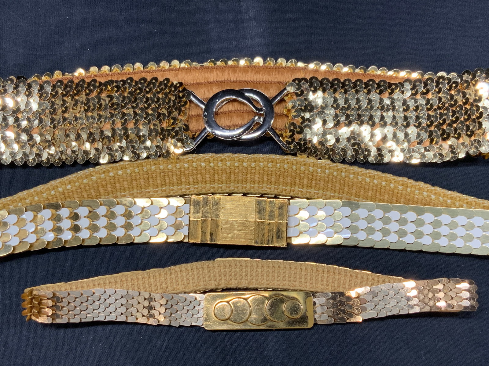 3 Vintage Brass Toned Fish Scale Belts: Lot of 3 vintage metal fish scale belts with gold toned buckles, smallest belt is approx 18 inches long, longest belt is approximately 30 inches long and 1 inch wide. And widest belt has sequins and w