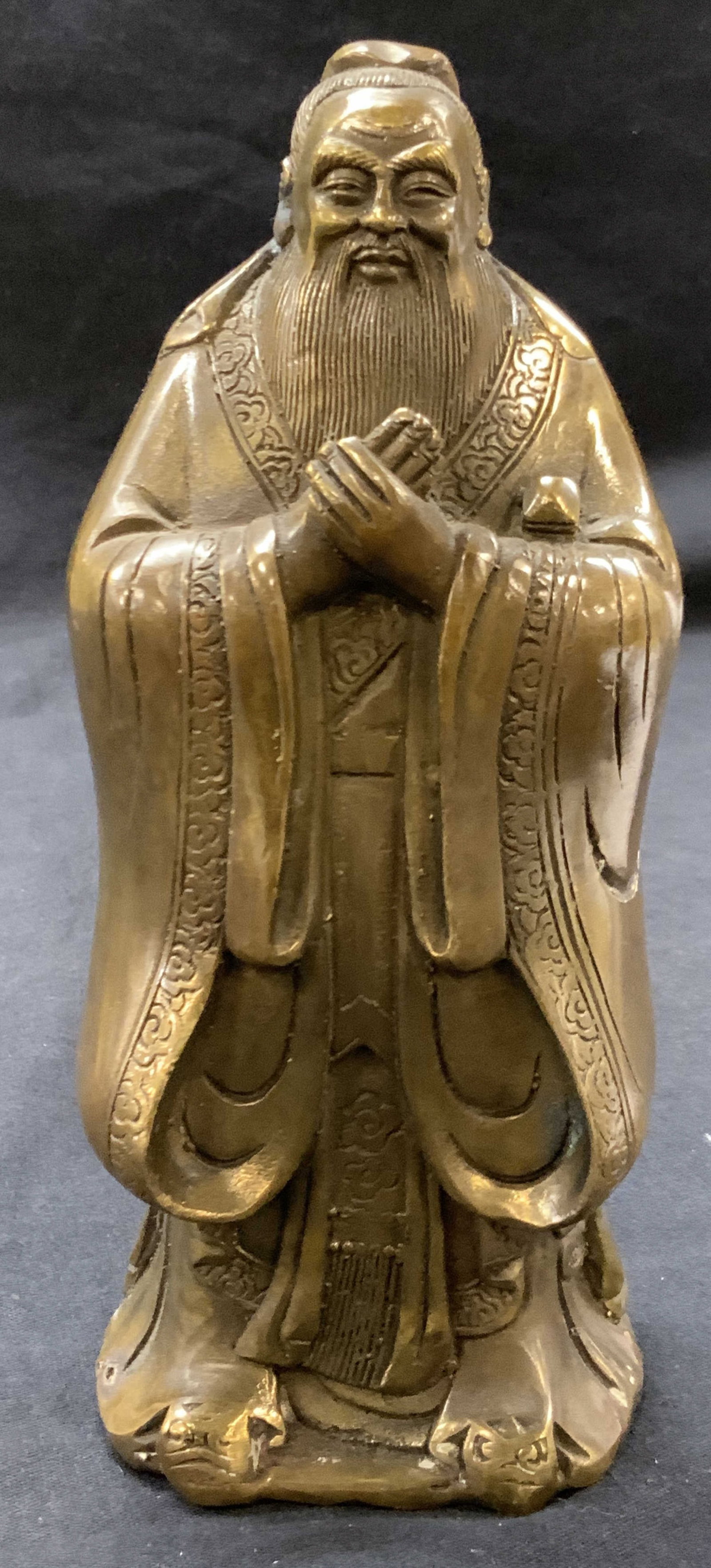 Cast Brass Confucius Figure: Cast brass, sculpture of Confucius with hand clasped in font of him Approximately 7.5 inches tall. Moderate wearing to sculpture and evident oxidation throughout. Cast metalworks, cast brass, Confuciu