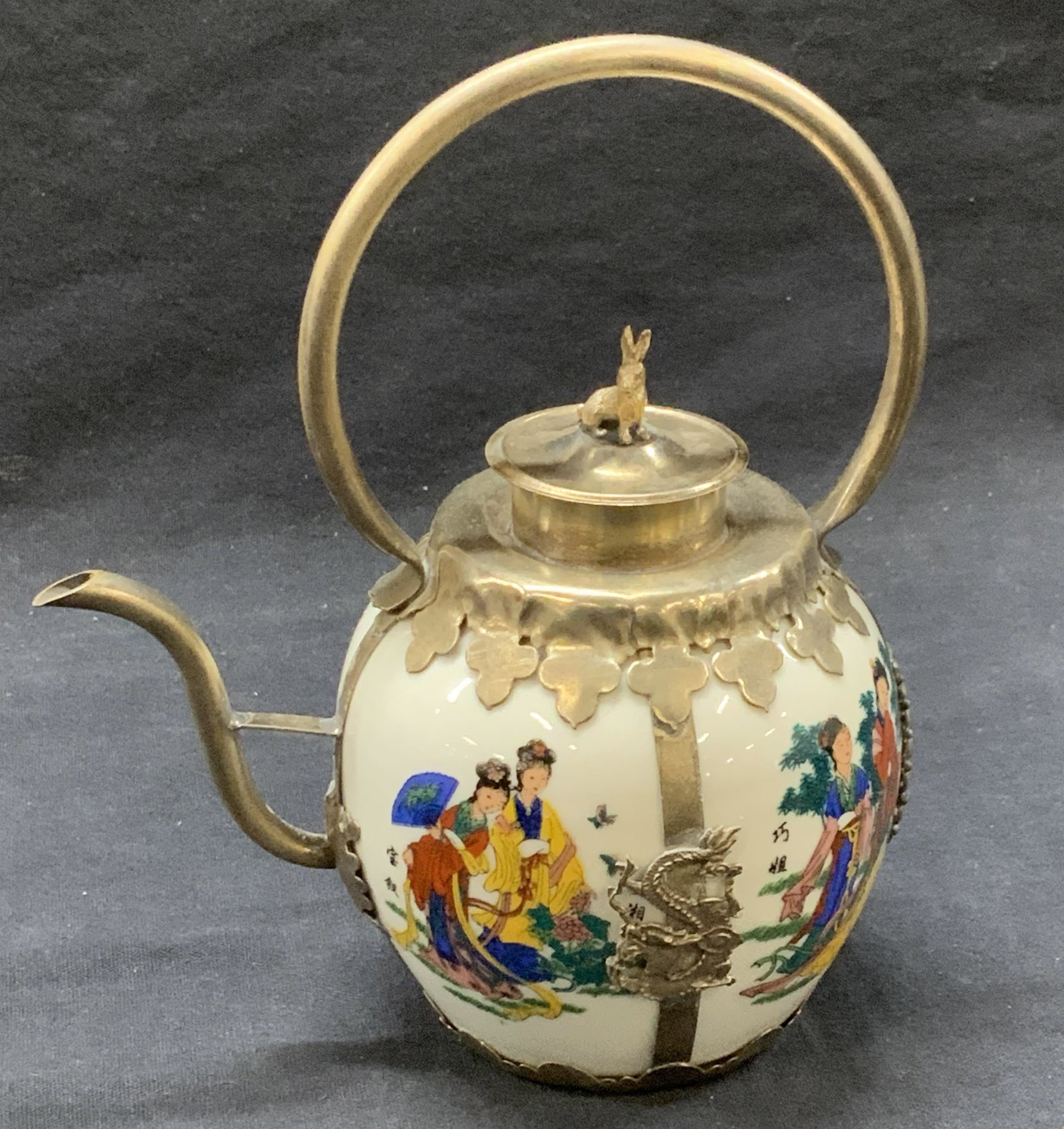 Hand Crafted Porcelain Asian Teapot, Bunny Finial: Asian teapot with Hand painted porcelain in white with Asian ladies dressed in traditional clothing. . Tibetan metal handiwork featuring Chinese dragons and a rabbit figurine finial., total width 5.25