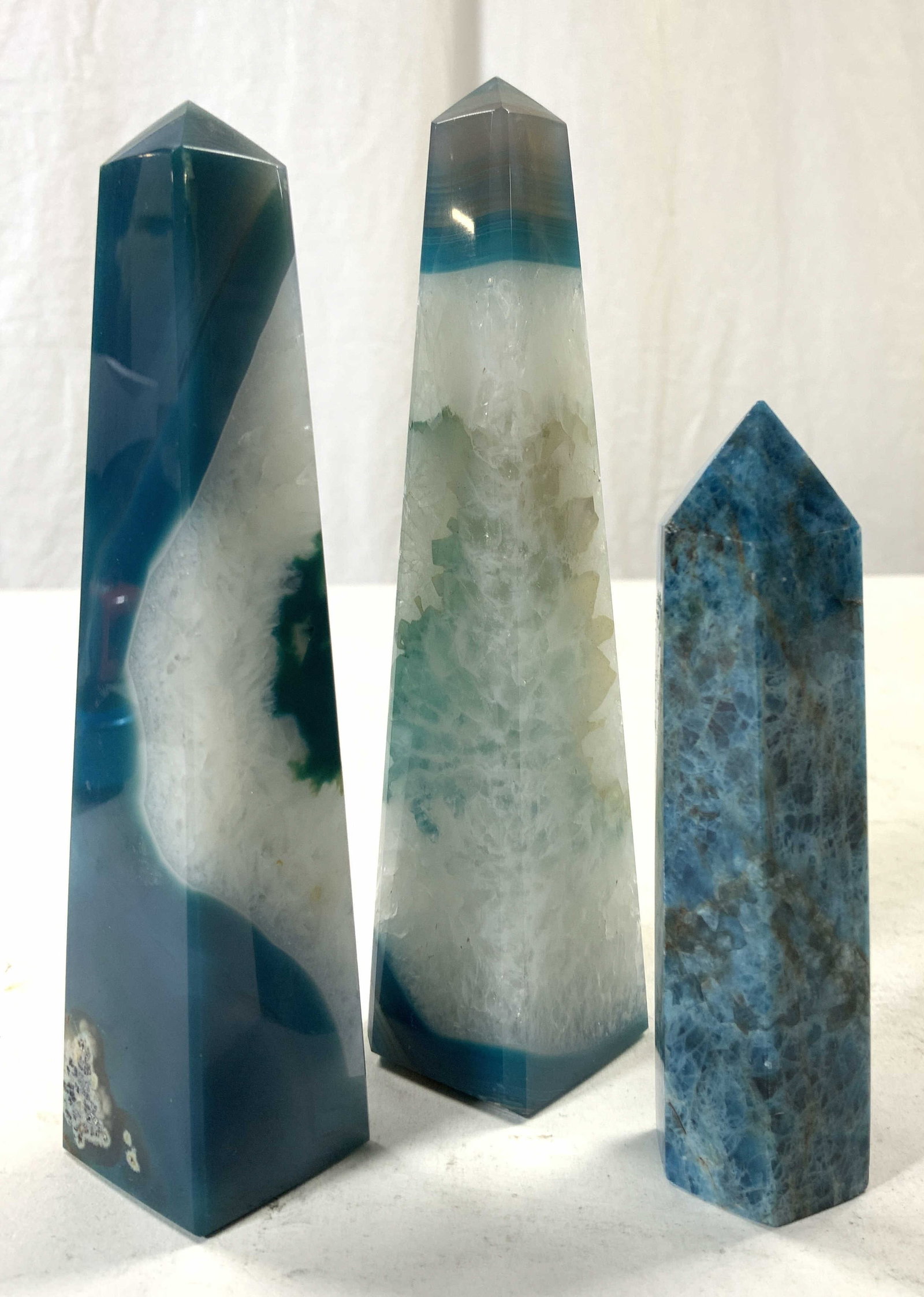 Group Lot 3 Natural Stone Agate Obelisks: Obelisk figures are natural stone appear to be agate. Each have blue & white toned banding. Largest piece in lot measures approx 5.75 inches tall 1.15 inches square at base. Obelisks, obelisk figures,