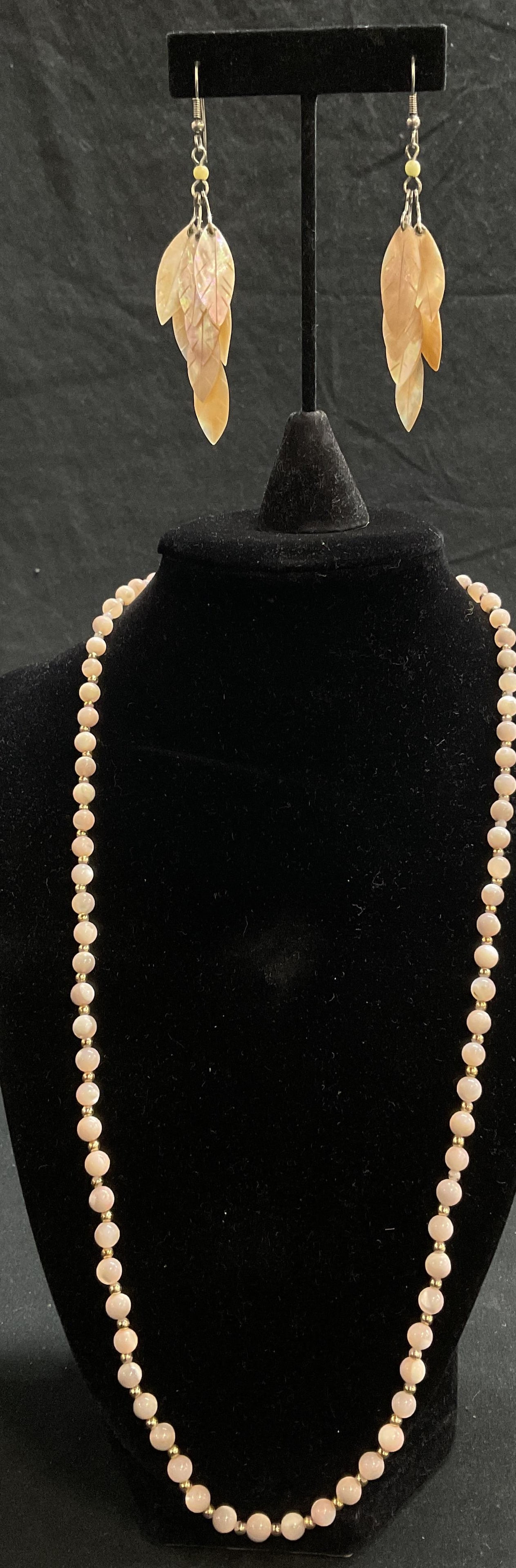 Lot 2 Mother of Pearl Earrings and Necklace: Vintage Pink coral with gold toned bead necklace. Drop Measures approx. 11.5 in. Vintage Pale pink mother of pearl leaf shape drop earrings. Measures approx. 3L in. Some surface wear consistent with a