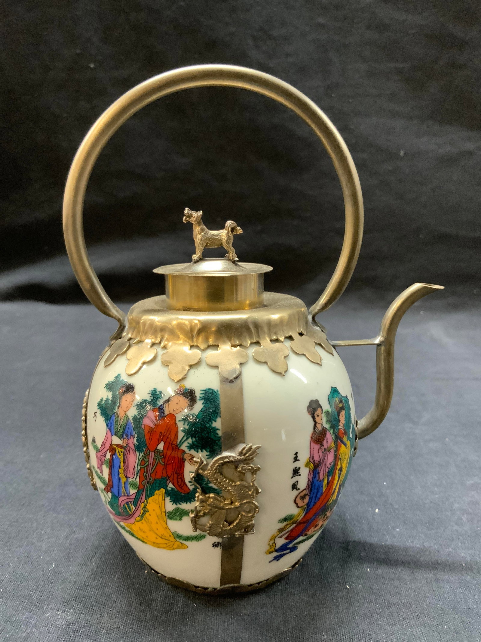 Hand Crafted Porcelain Asian Teapot, Dog Finial: Asian teapot with Hand painted porcelain in white with Asian ladies dressed in traditional clothing. . Tibetan metal handiwork featuring Chinese dragons and a rabbit figurine finial., total width 5.25