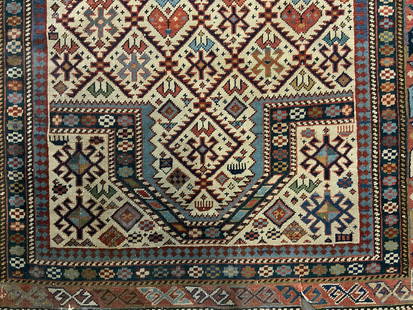 Vintage Handmade Caucasus Rug: A vintage handmade Caucasus rug featuring an off white background with bold geometric patterns to the center and the border. Appears to be hand knotted and crafted from wool. Measures approx. 34W x 51