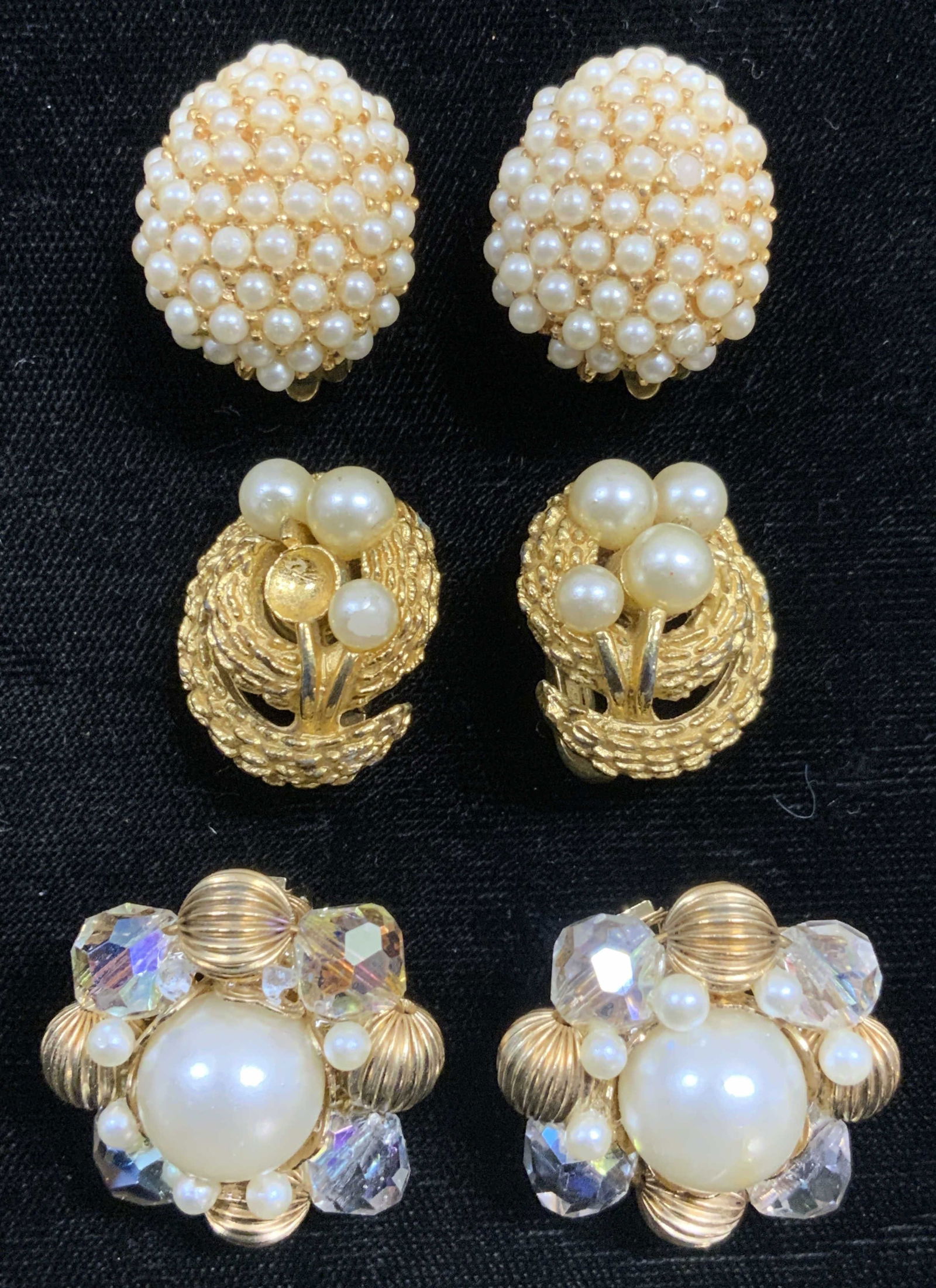 Lot 6 Pearlescent Assorted Clips On Earrings: One pair inscribed MARVELLA .75 inches wide 1 inch tall, 1 pair inscribed TRIFARI .75 Inches wide. Third pair measures approx 1.15 inches wide & tall. Lot includes 6 clip on earrings, each are gold to