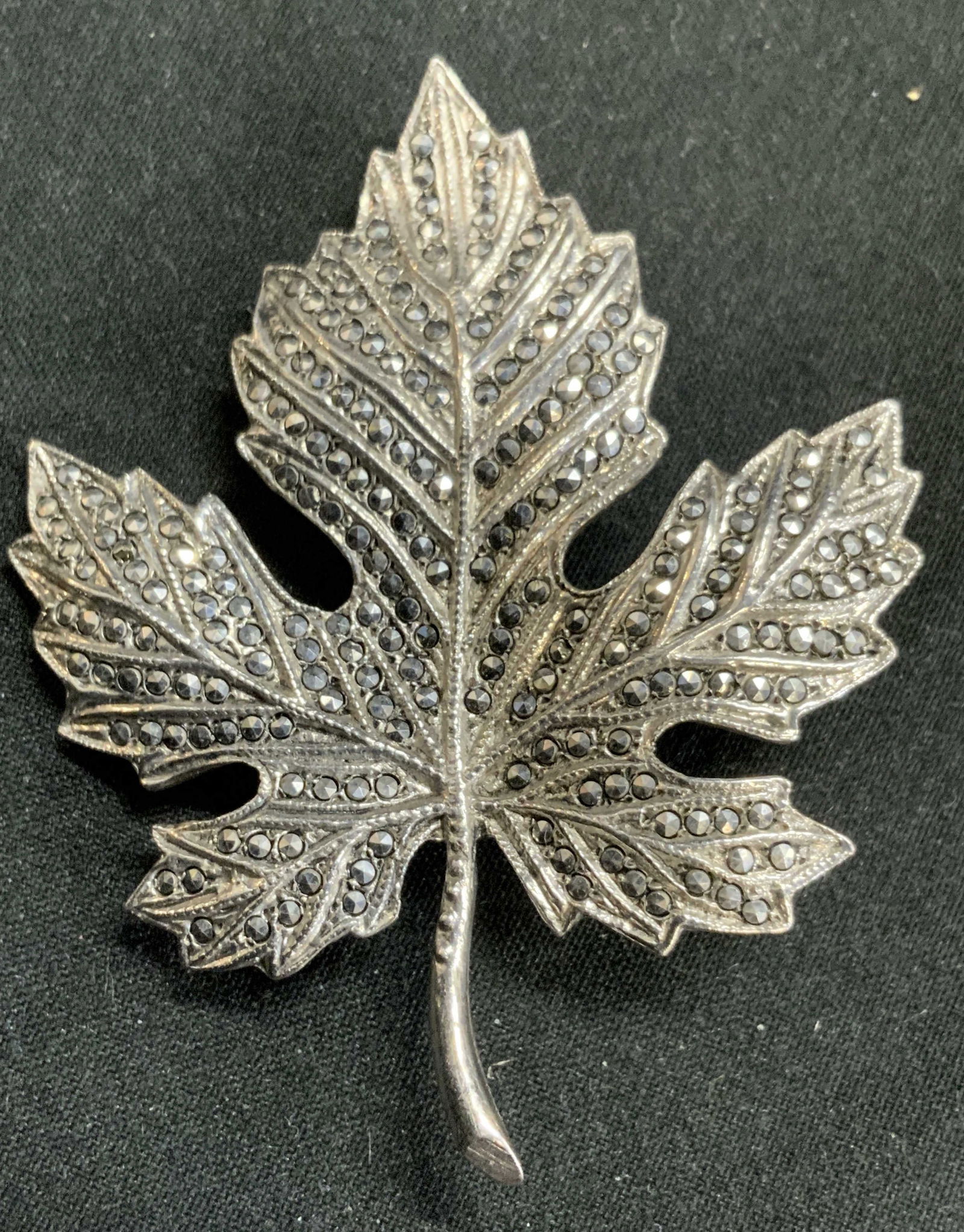 Maple Leaf Brooch Pin W Rhinestones: Brooch pin is silver toned white metal. Piece has maple leaf shape. Brooch has what appears to be rhinestone detail. Piece measures approximately 2.15 inches tall 1.65 inches wide. Brooch, brooch pin,