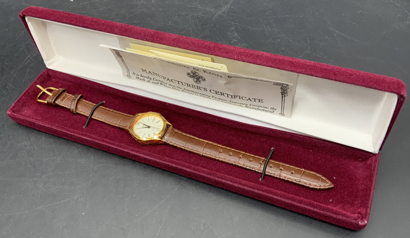 Camrose & Kross JBK Wristwatch W/ Original Box: Vintage Camrose & Kross JAQUELINE BOUVIER KENNEDY wristwatch with original box and certificate. The watch is crafted from brown leather and features a white face rimmed with gold tone metal, possibly 
