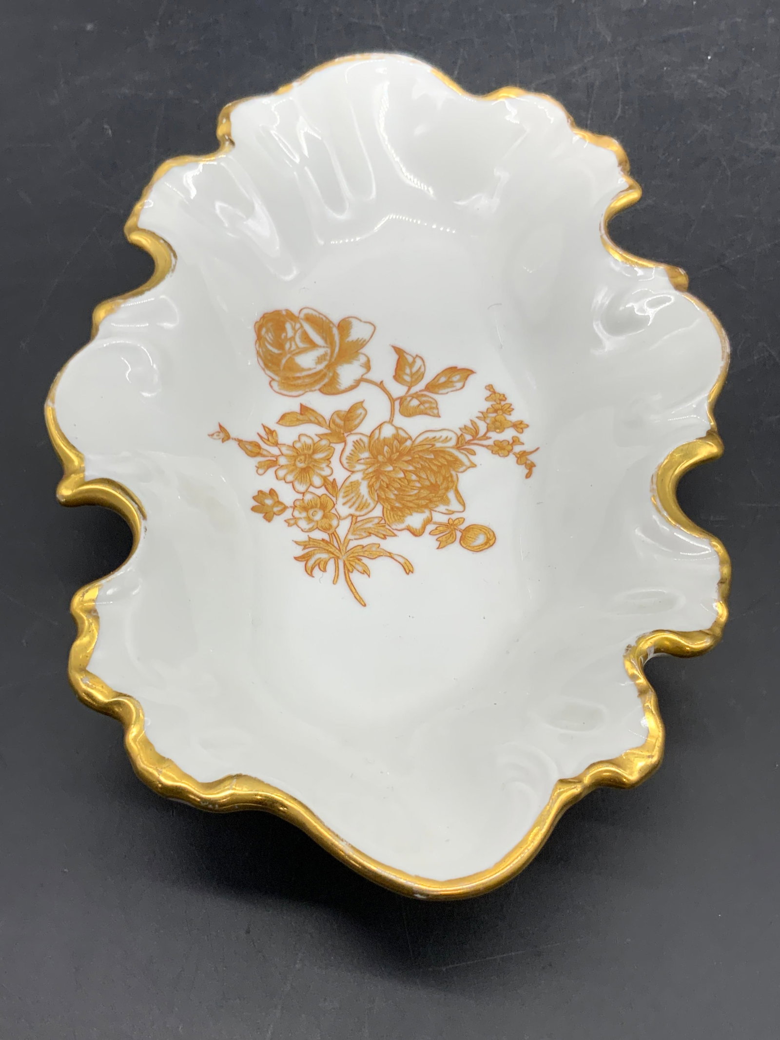 LIMOGES FRANCE Porcelain Floral Scalloped Dish: A thick walled porcelain dish with a scalloped rim. Gilt floral motif to the center and gilt line work to the trim. Underside signed LIMOGES FRANCE. Measures approx. 1.5H x 9W in. Measured at widest p