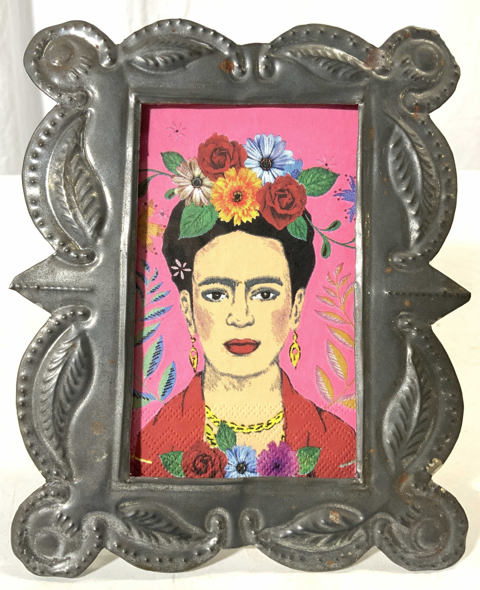 Vintage Picture Frame W Frida Kahlo Portrait Print: Picture frame is vintage. Piece is silver toned metal, possibly white metal. Has printed portrait of Frida Kahlo, appears to be a printed paper napkin, not inspected outside of the frame. Backside has