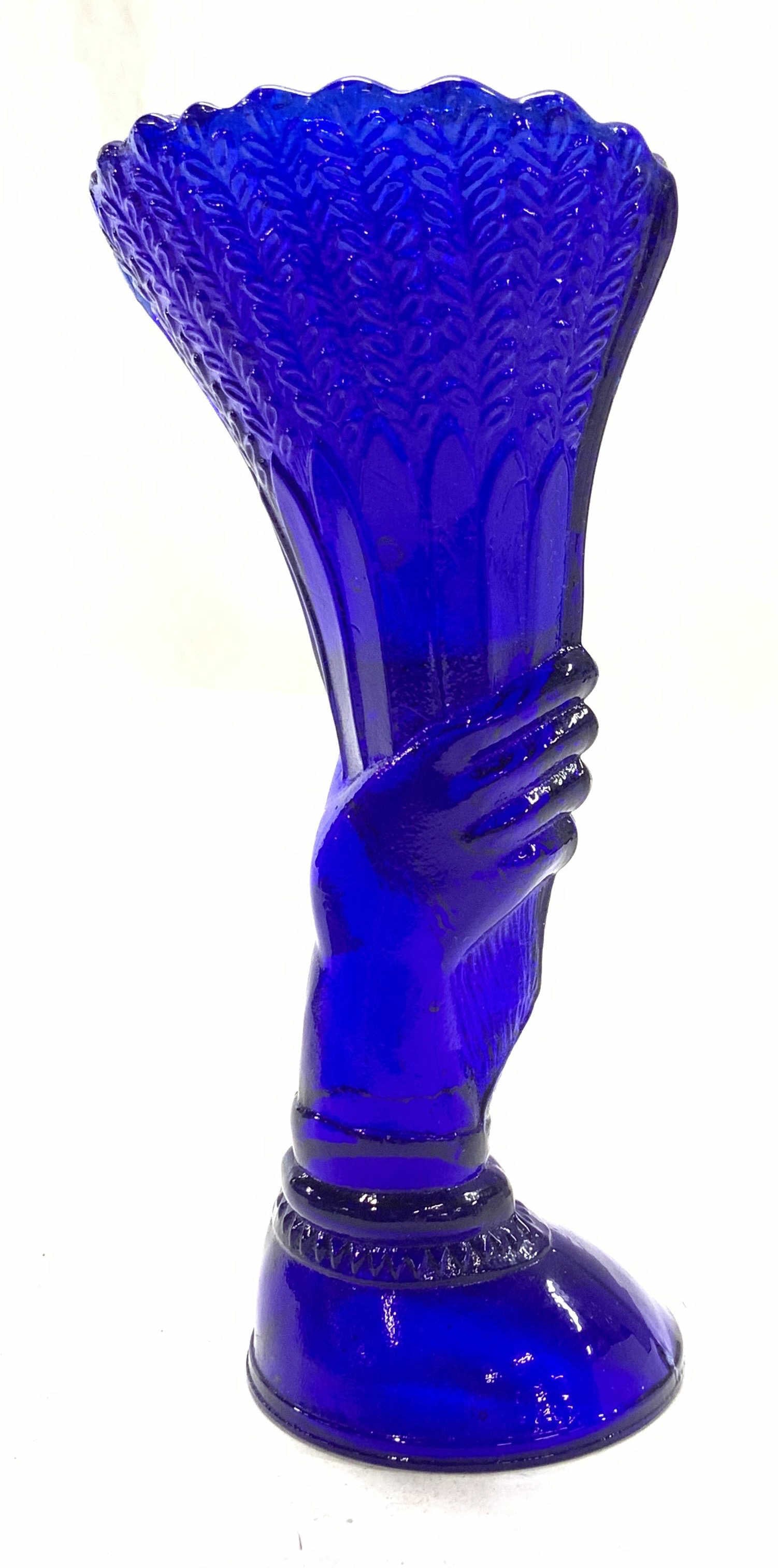 Cobalt Blue Glass Vessel with Hand Over Wheat: Fenton style cobalt vintage molded glass vessel, hand gripping a wheat bungle. Vase depth stop half way to top of hand. Measures 6.5 in. Tall, base 2.5 in. , top measures 3 x 2 in. Embossed glass vase