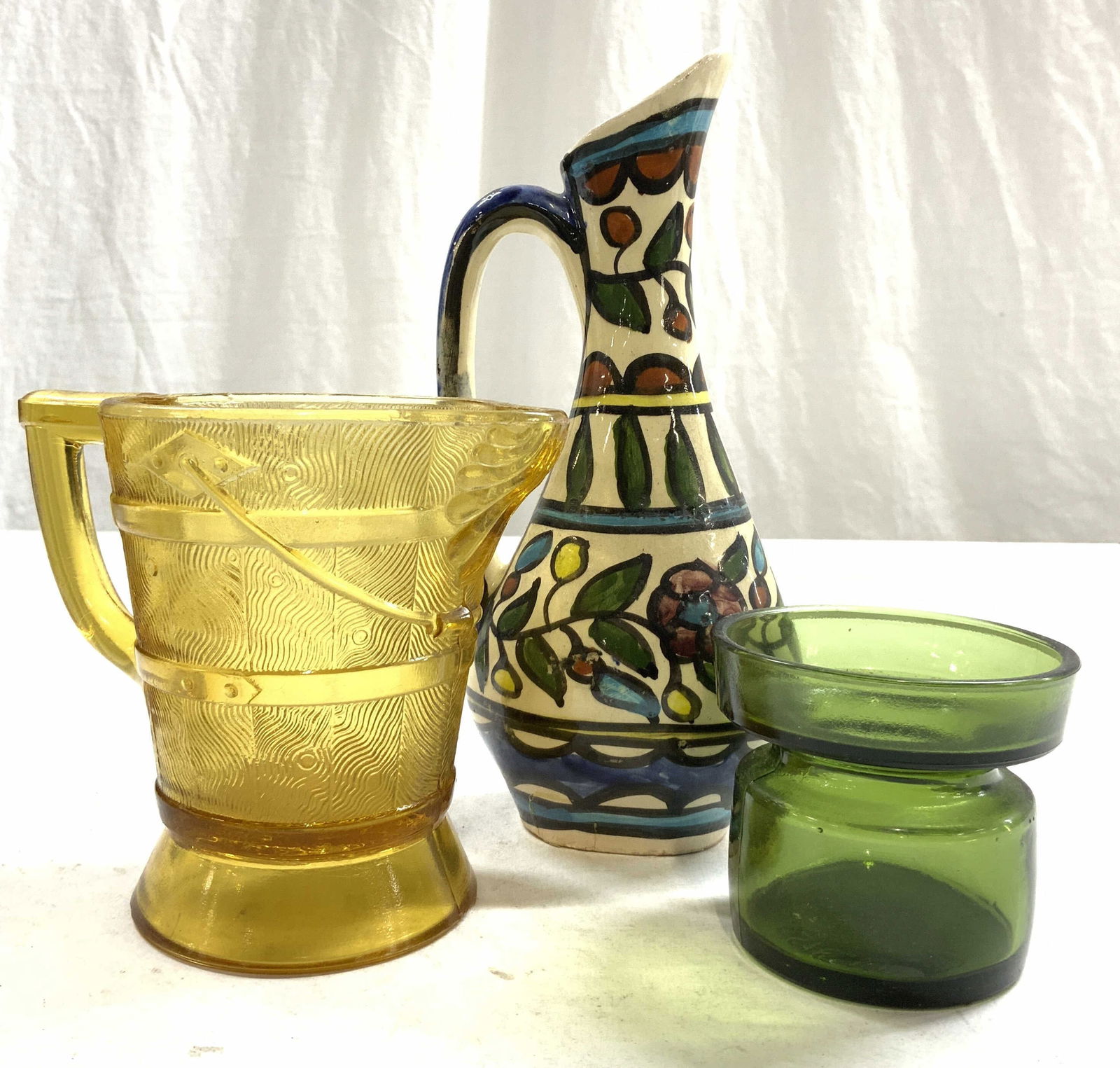 Lot 3 Porcelain & Glass Vessels, DANSK More: Lot includes 1 pitcher with barrel detailed exterior, 1 green glass vessel, & 1 hand painted porcelain Ewer. Underside of green vessel reads DANSK DESIGNS LTD. Porcelain Ewer measures approx 8 inches