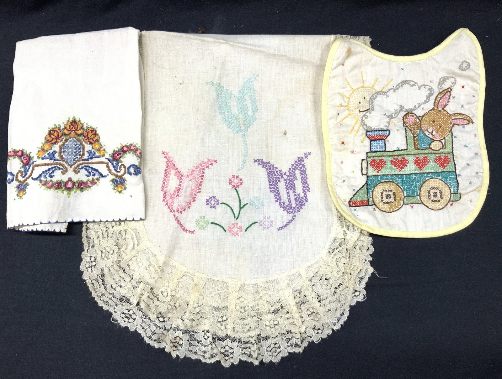 Lot 3 Vntg Cross Stitch Home Accessories, Linens: Lot of 3 vintage cross stitch home accessories. 1 baby bib with cross stitch and embroidery image of a rabbit on a train. Approx,9 x8 inches. 1 tea towel with cross stitch pattern of ornate scrolls wi