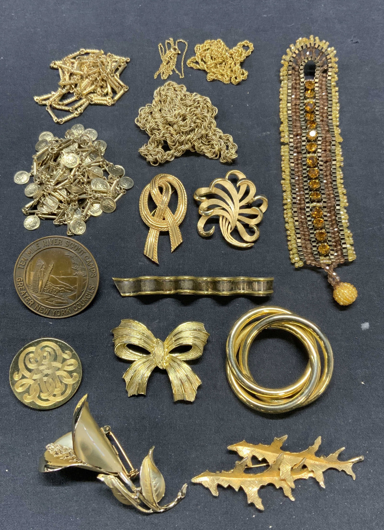Lot 15 Sterling Silver, Trifari, More Jewelry: Lot of 15 jewelry pieces. Sterling silver and gold plated brooch. Marked Mexico, 925 to underside. Measures approx. 3 3/8 x 3/8 inches. Total weight .50 ozt. 2 gold tone Trifari ribbon brooches. Both 