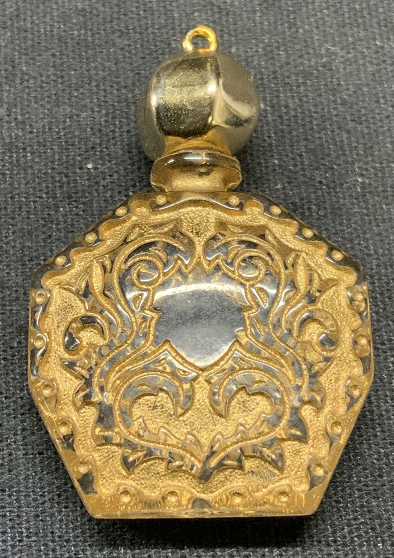 Gold Tone Bottle Pendant: Gold tone scroll motif bottle pendant. Acrylic. Top appears stuck. Measures approx. 1 x 1/8 x 1.5 inches. Scratching observed. Estate jewelry, costume jewelry, cocktail jewelry, fashion jewelry, acces