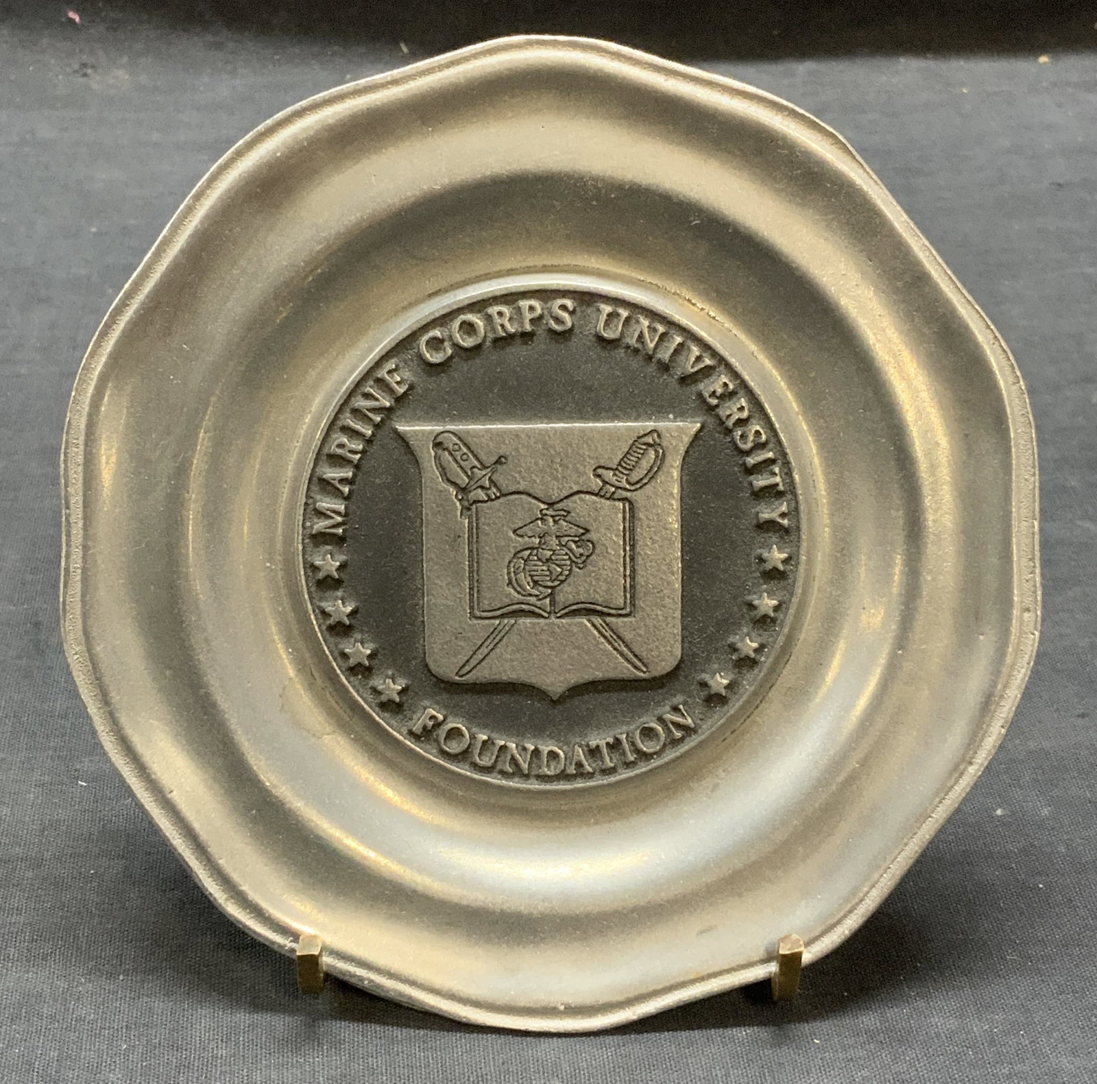 Marine Corps University Foundation Pewter Plate: Marine Corps University Foundation pewter plate. Measures approx. 5.5 inches diameter. Some surface wear consistent with exposure. Marine corps university foundation, marine corps university, marine c