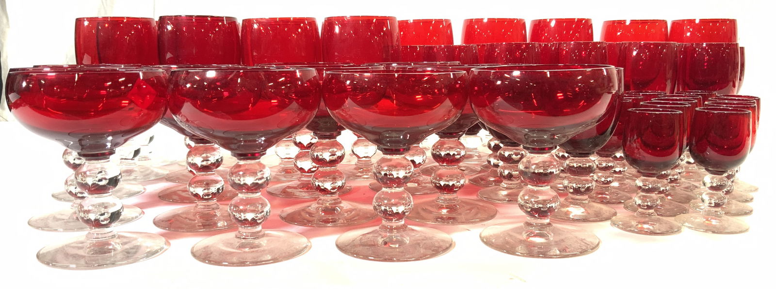 Set 55 Cranberry Glass Stemware: Lot includes 15 cordial glasses 13 wine glasses, 12 cocktail glasses, 10 flutes, 4 mid size goblets, 1 goblet is slightly larger than other 3. Each glass has cranberry toned basin & clear stems. Large