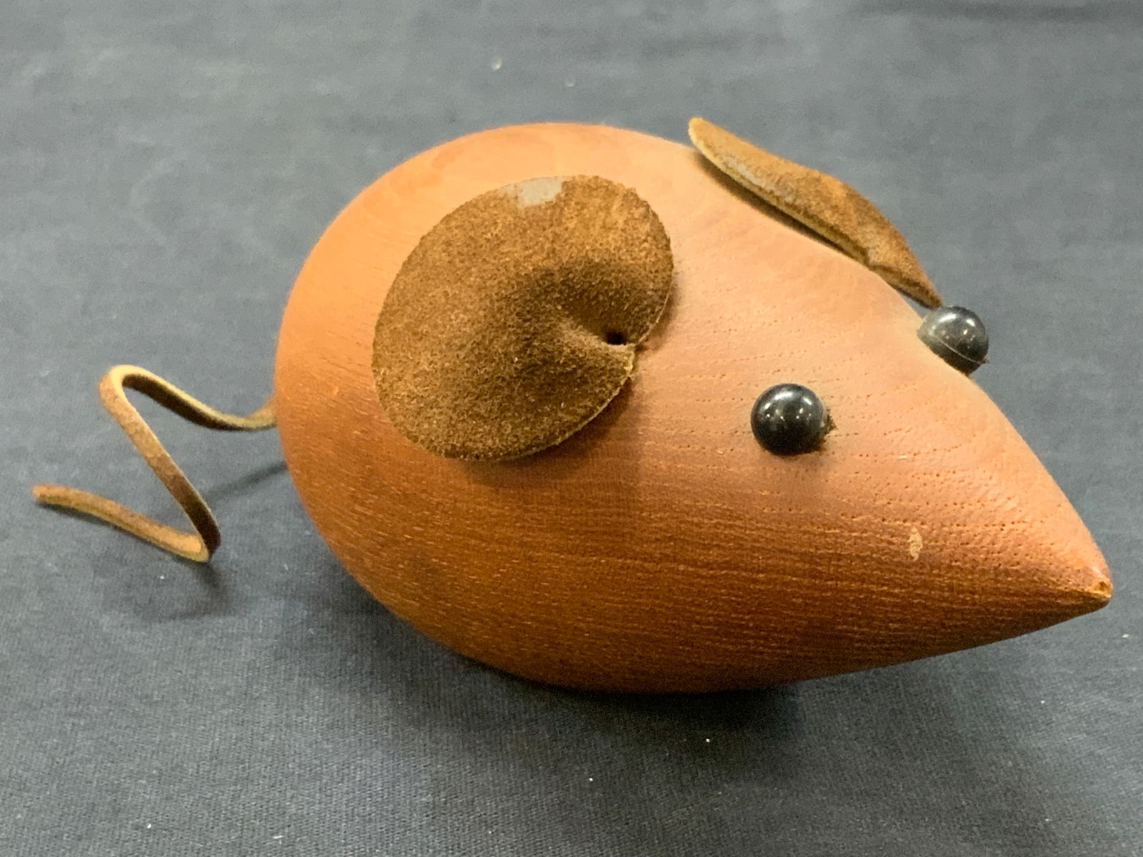 Crafted Wooden & Suede Mouse, West Germany: Marked on underside West Germany. A mouse figure made of wood with suede wears and tail. Approx 5 inches long, not including the tail. Moderate wearing to wood and leather ears. Wooden figure, wooden
