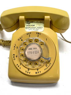 Bell System Western Electric Rotary Phone: Vintage yellow rotary table top telephone., heavy , c. 1960s- 1970s. Dial for ring loudness. Phone connected to plug with wire , foreign country 4 prong plug. Wear to exterior, crack on front. Phone m