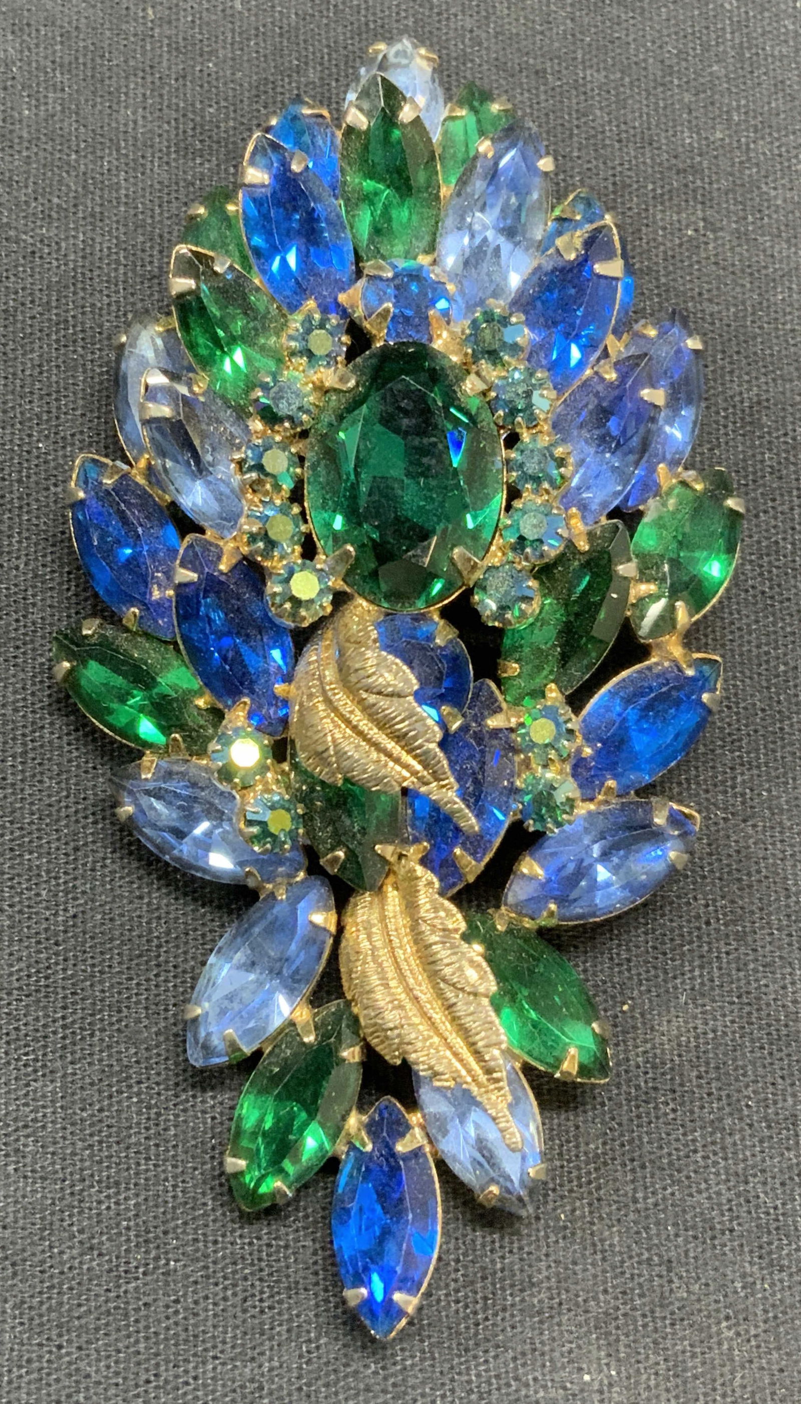 HATTIE CARNEGIE Blue & Green Crystal Brooch: Vintage Hattie Carnegie blue and green toned crystal decorated brooch. Signed to underside. Measures approx. 3.5 x 1.75 inches. Some surface wear including scratching observed. Hattie Carnegie began m