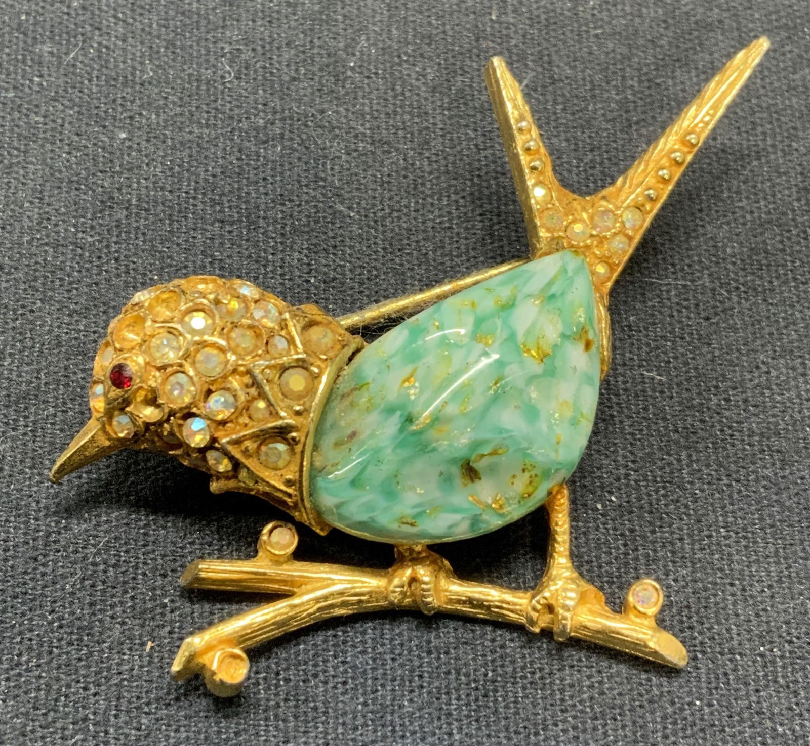 JEANNE Gold Tone Crystal Bird Brooch: Vintage Jeanne gold tone crystal and blue lucite Cabochon brooch. Signed to underside. Hinge pin to underside. Measures approx. 1.75 x 2 inches. Some surface wear including scratching and loss to crys