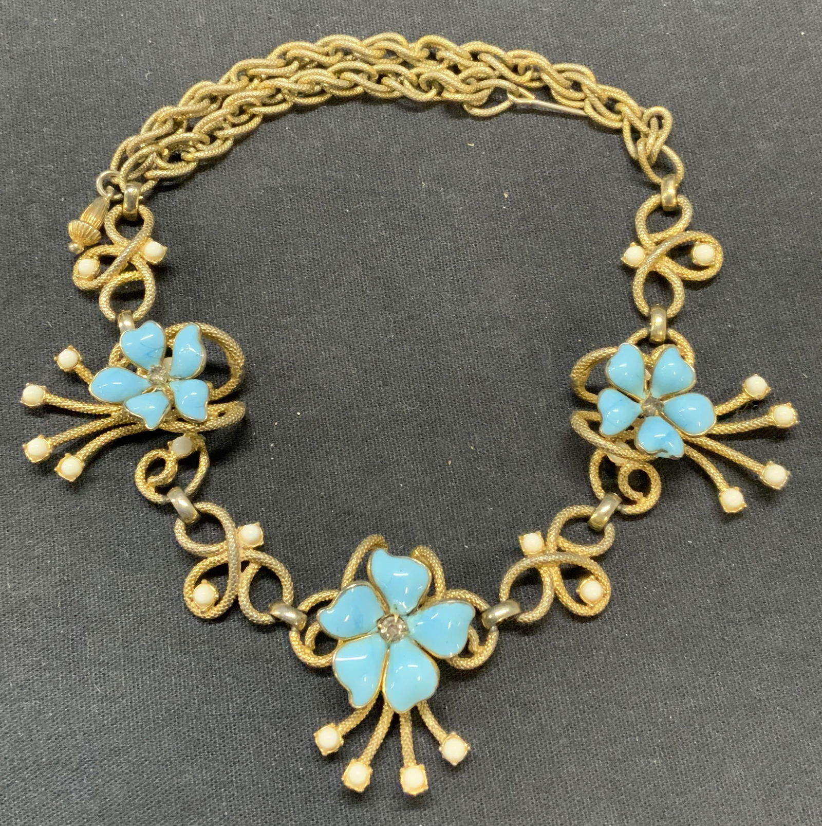 SCHIAPARELLI Gold Tone Floral Necklace: Vintage Schiaparelli gold tone necklace with floral pendants and blue and white lucite decoration. Signed to underside. Drop length approx. 7 inches. Some surface wear including scratching observed. E
