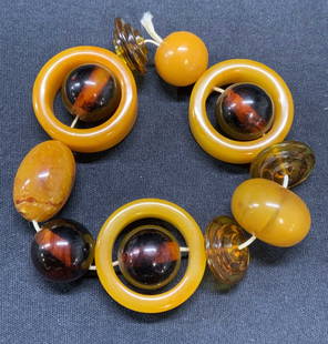 Amber & Bakelite Beaded Stretch Bracelet: Vintage amber and Bakelite beaded stretch bracelet measures approx. 2.75 inches wide, stretches wider. Dark colorless round amber beads fluoresce under UV light. Some surface wear including scratching