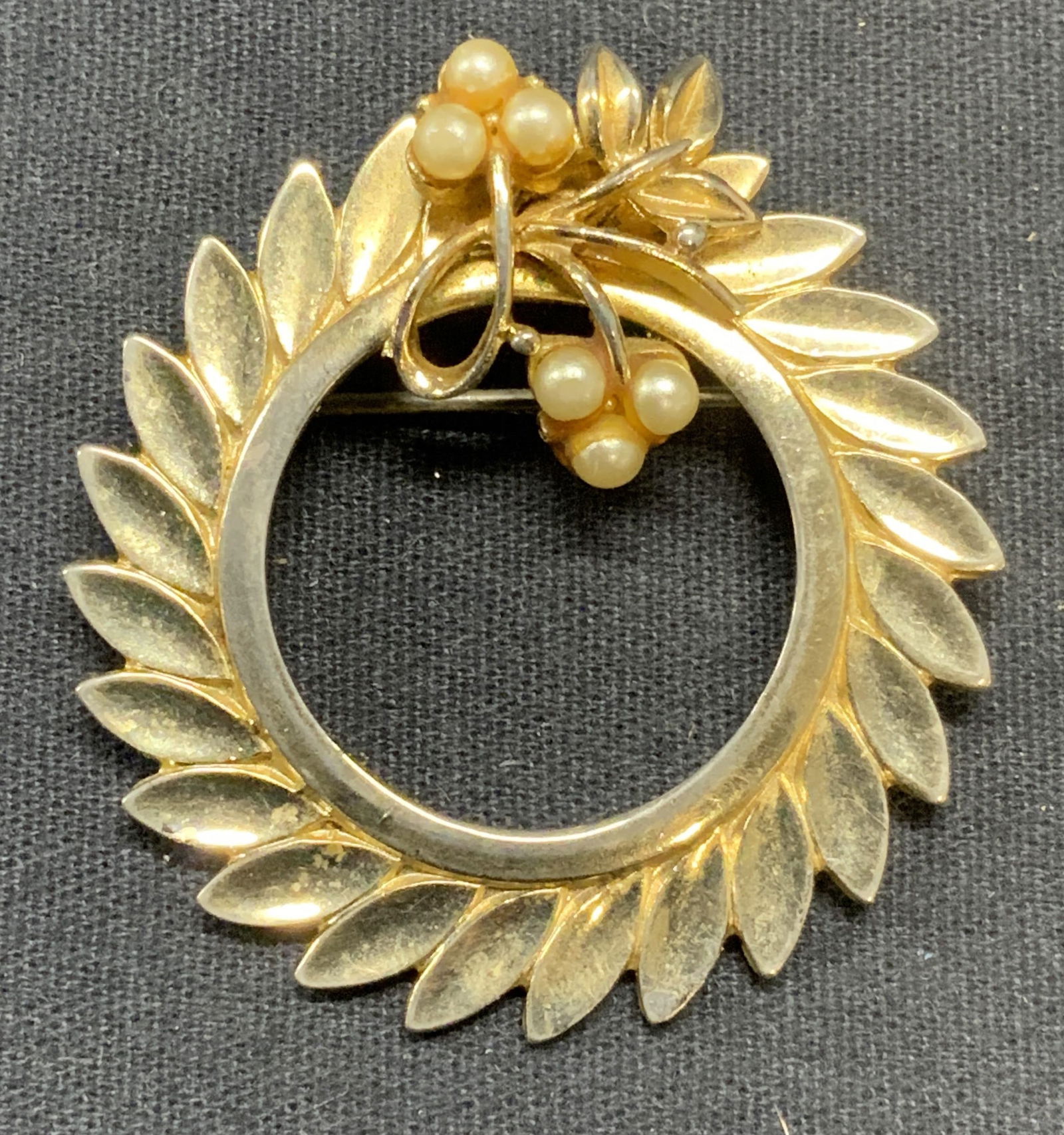 CORO Gold Tn Faux Pearl Wreath Brooch: Vintage Coro gold tone faux pearl decorated wreath brooch. Signed tomunderside. Hinge pin to underside. Measures approx. 1 5/8 inches diameter. Some surface wear including scratching observed. Estate