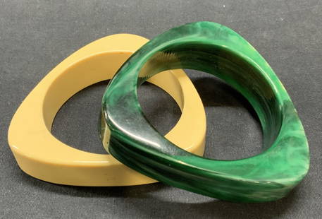 2 Cream & Green Bakelite Triangle Bangles: Lot of 2 jewelry pieces. Cream and malachite green toned chunky triangle bangle bracelets. Possibly Bakelite or celluloid. Measure approx. 2 5/8 inches interior diameter, 3 5/8 inches wide. Some surfa