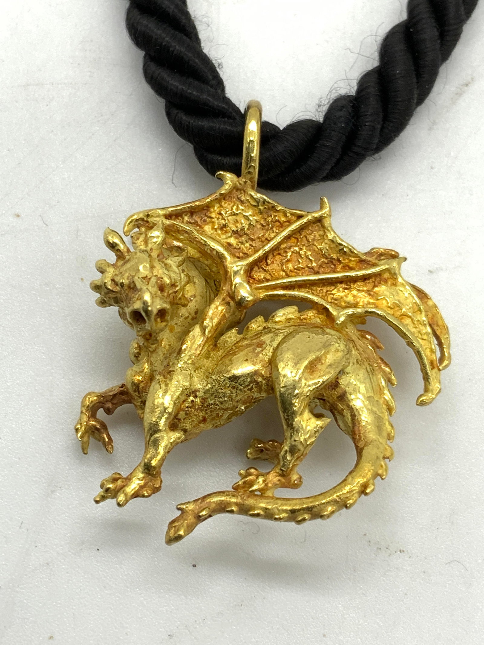 Gold Tone Dragon Figural Pendant Necklace: Gold tone dragon pendant necklace on black twisted rope cord. Drop length approx. 8 inches. Pendant measures approx. 1 1/8 x 1 1/8 inches. Some surface wear including scratching observed. Estate jewel