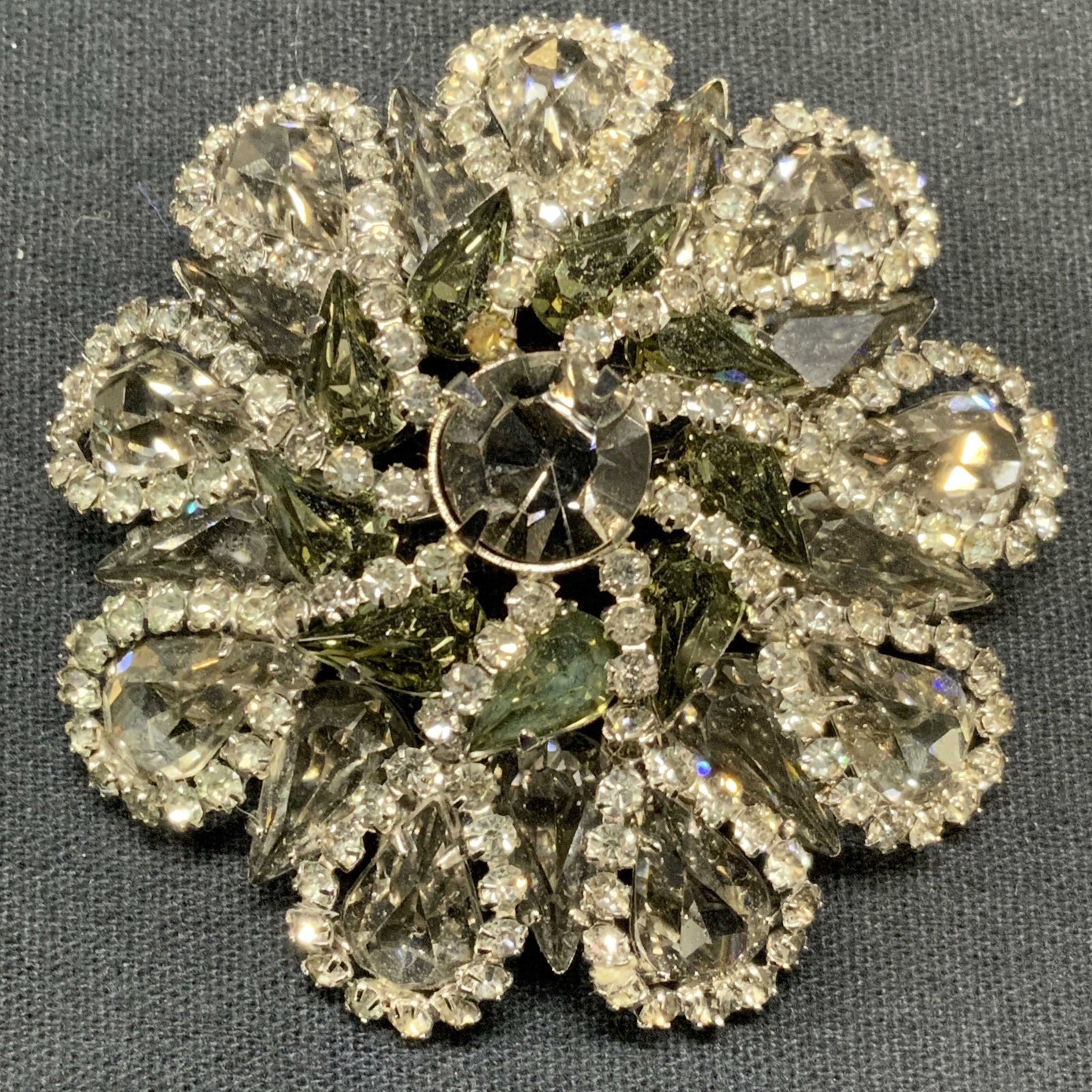 WEISS Silver Tone Crystal Flower Brooch: Vintage Weiss silver tone colorless and grey toned crystal flower brooch. Signed to underside. Hinge pin to underside. Measures approx. 2.25 inches diameter. Some surface wear including scratching obs