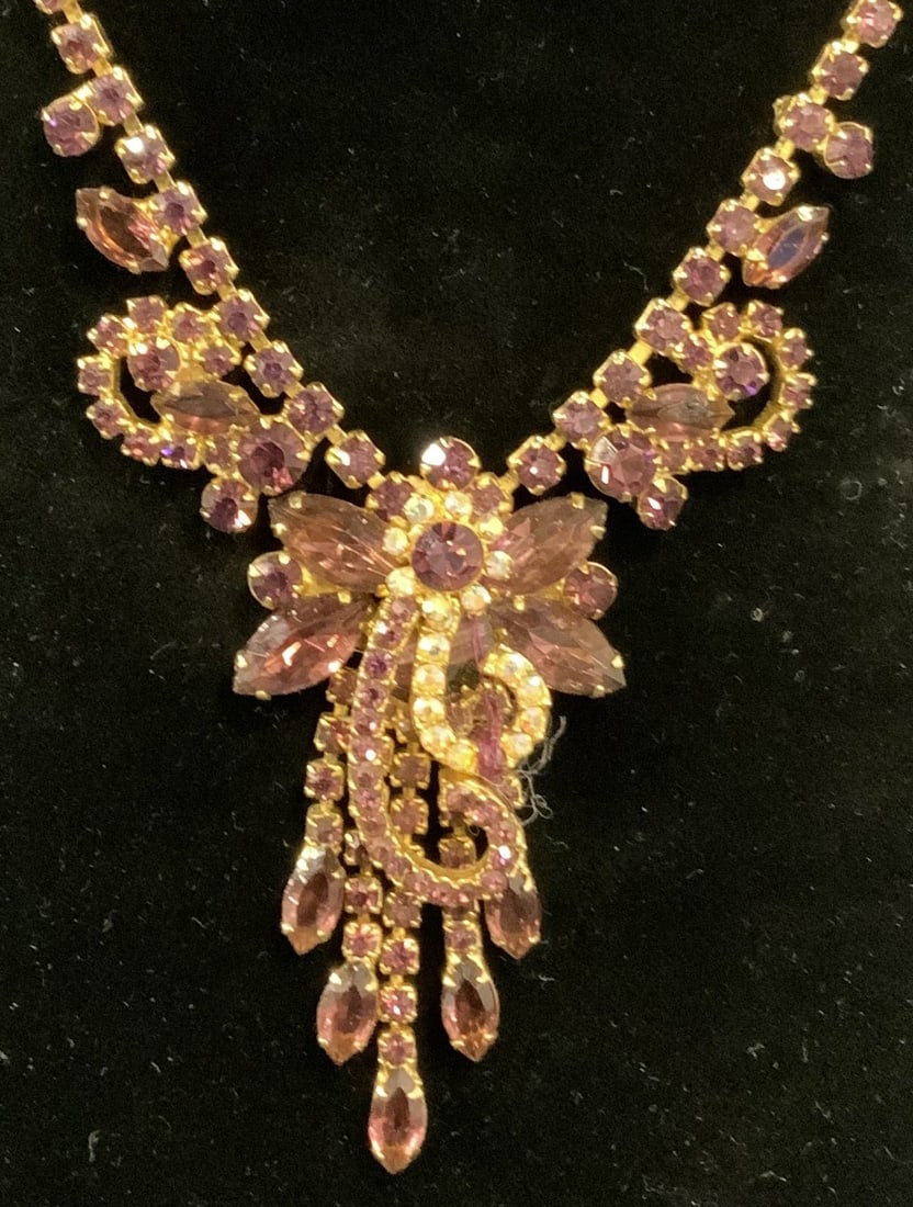 Gold Tone Purple Crystal Flower Necklace: Gold tone purple crystal necklace with flower motif. Drop length approx. 9 inches. Some surface wear including loss to finish and scratching observed. Estate jewelry, costume jewelry, cocktail jewelry